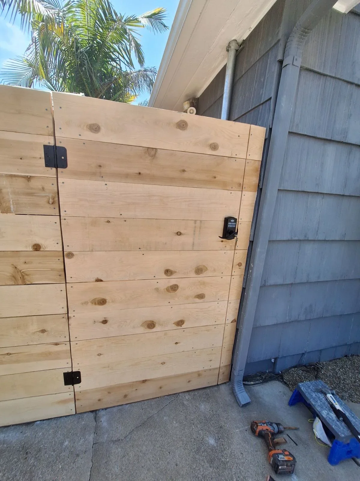 Horizontal wood shiplap gate with keypad access and black hardware hinges