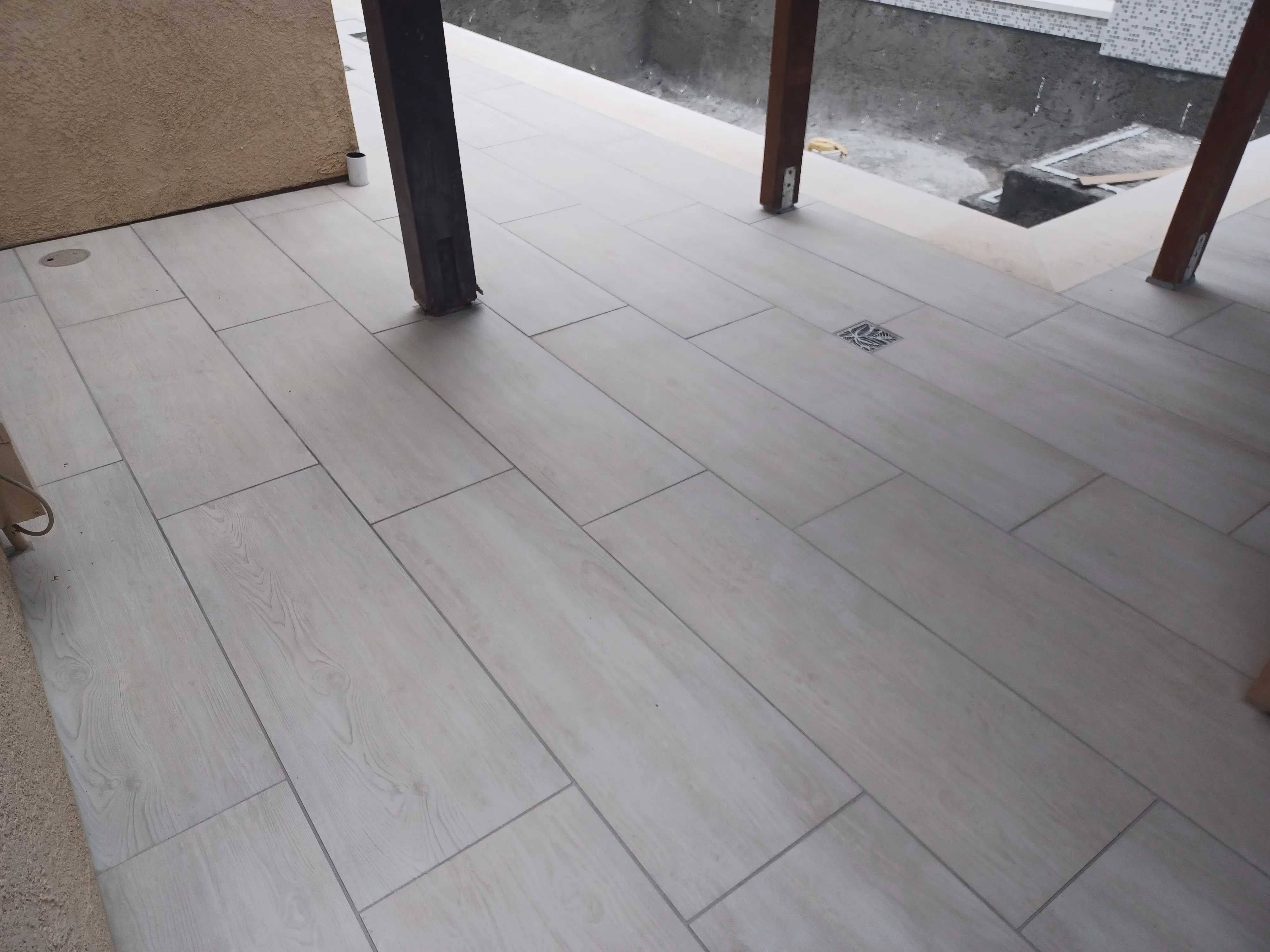 Large format porcelain pavers in herringbone pattern with wood-look finish and gray grout joints