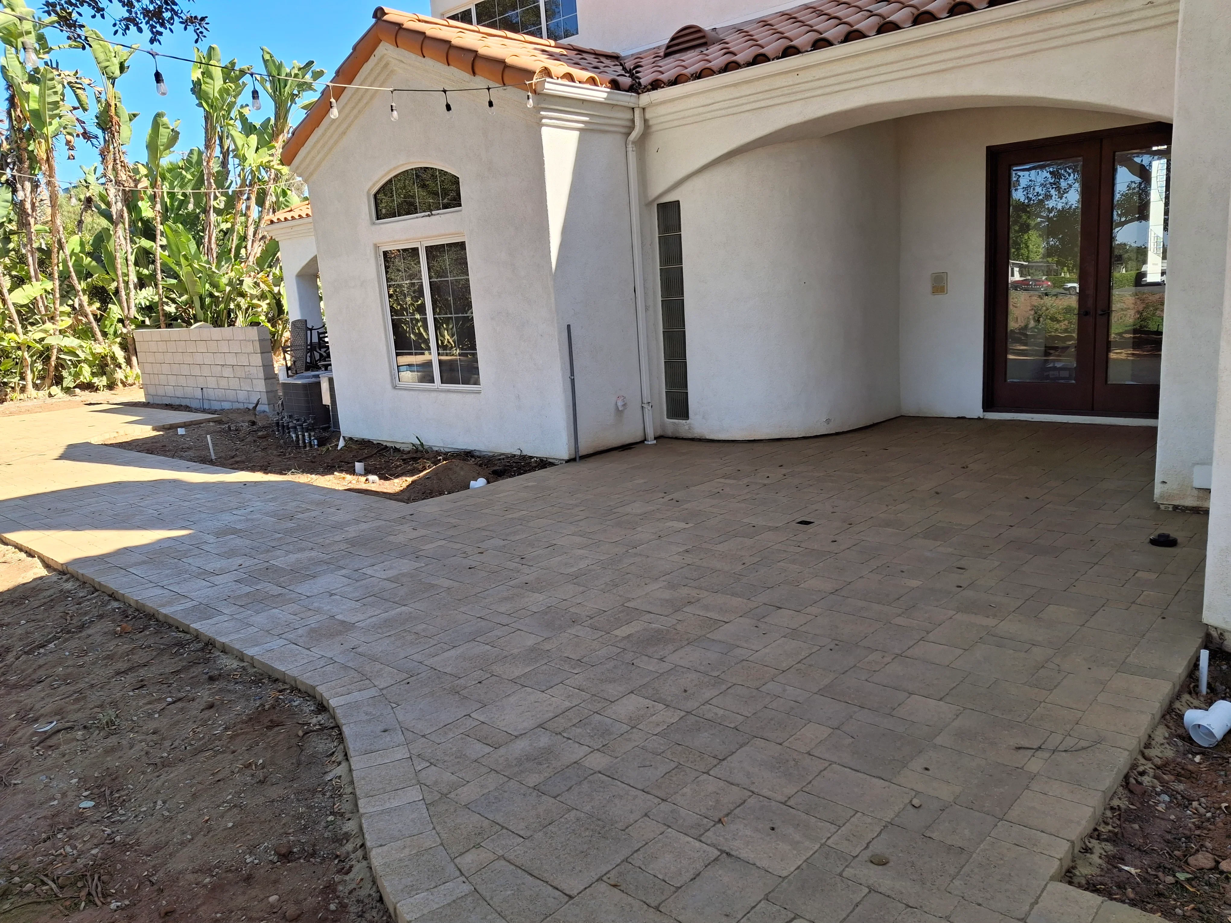 Concrete paver patio with running bond pattern adjacent to white stucco home