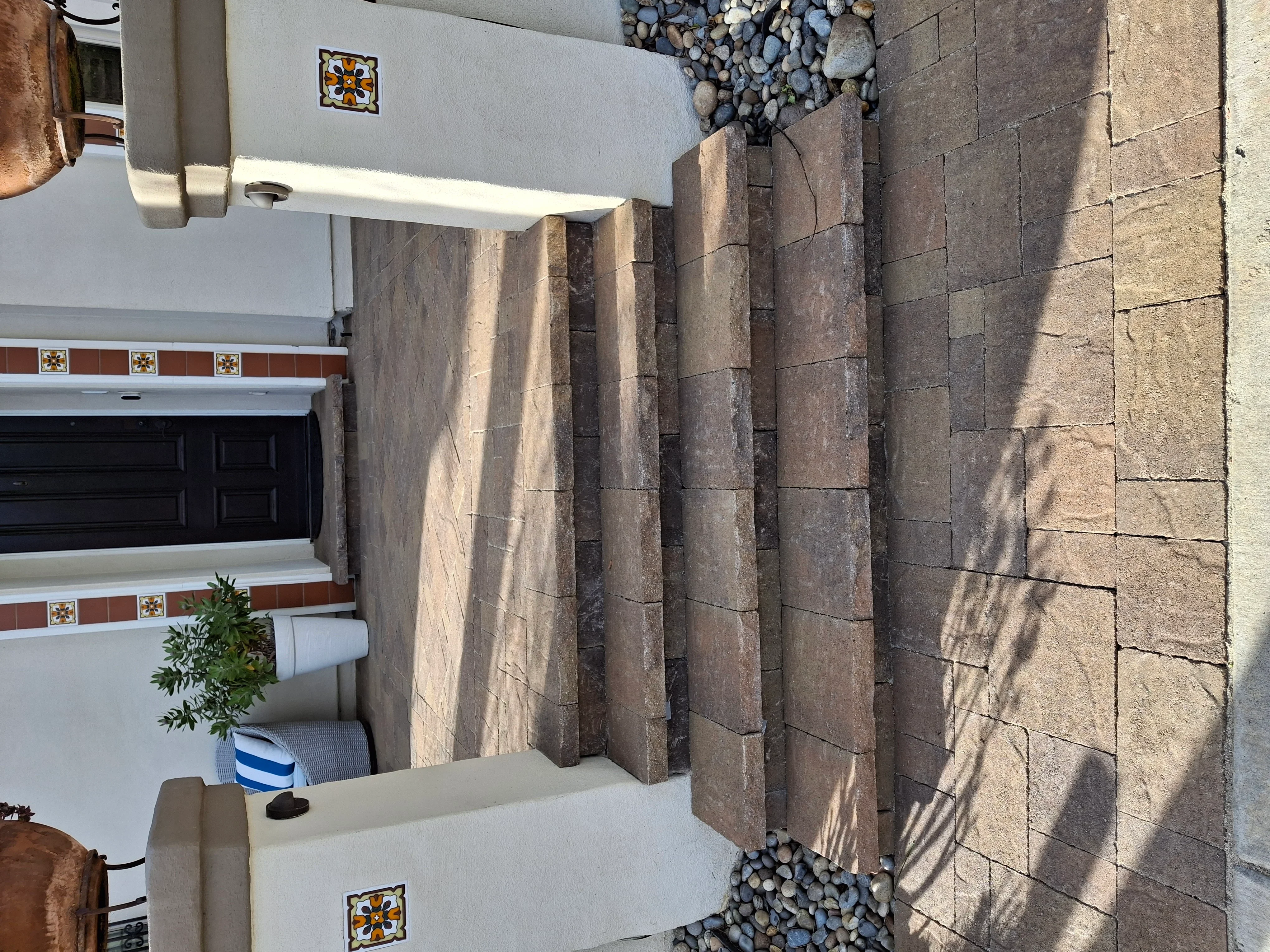 Stacked stone paver accent wall with vertical rectangular blocks and decorative tile trim