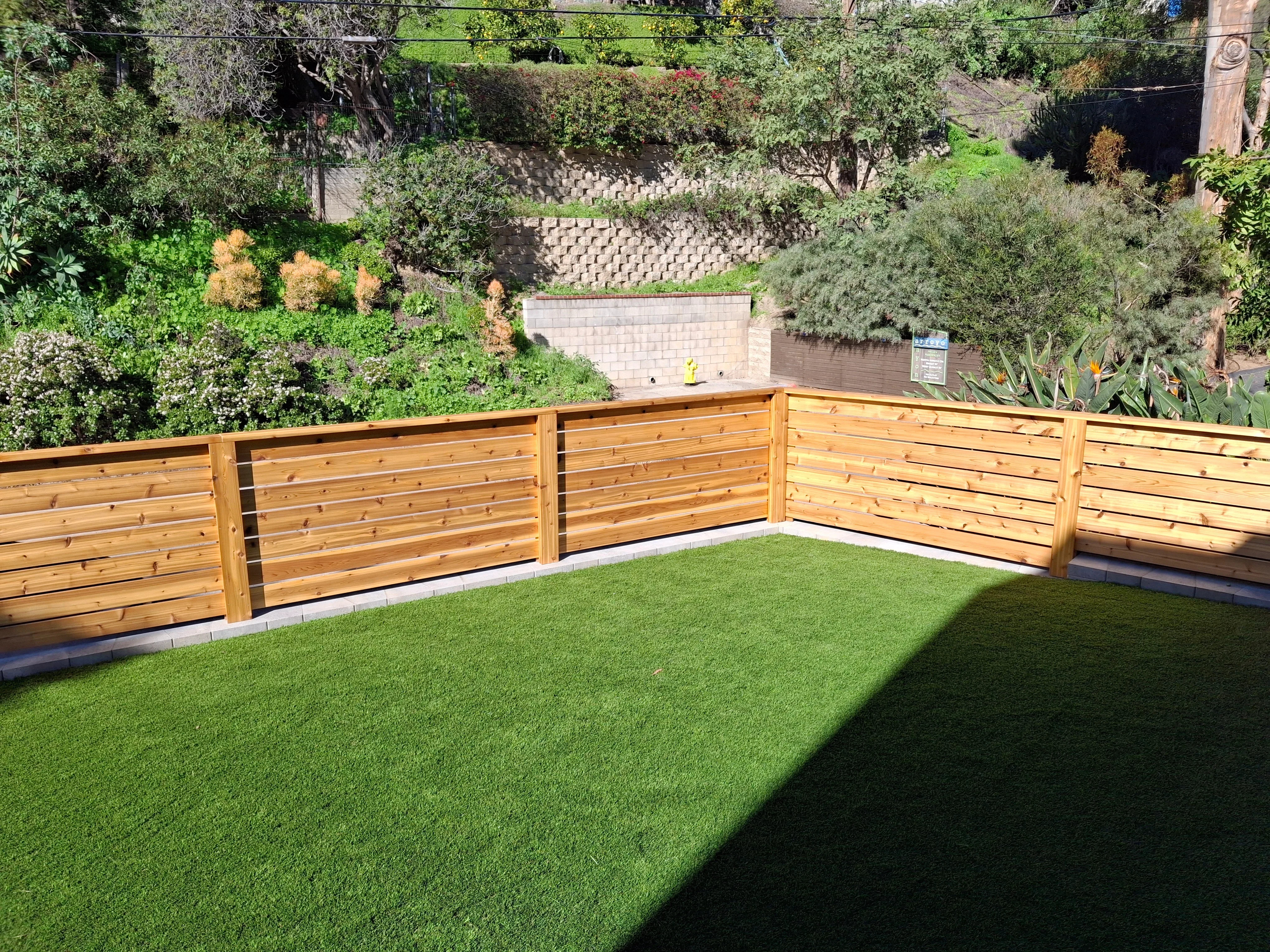 Horizontal wood fence with metal rods and synthetic turf lawn installation