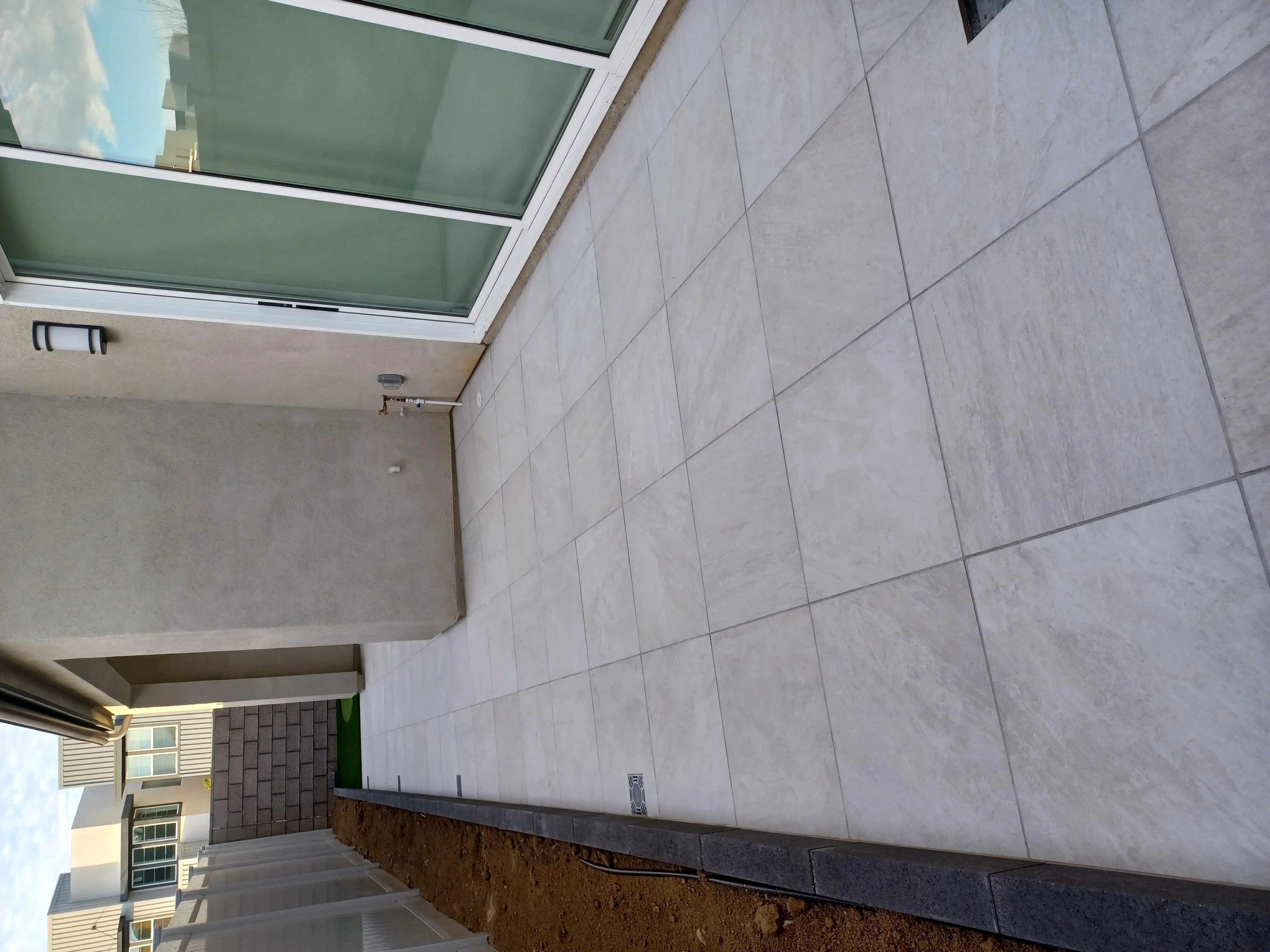 Large format gray pavers installed in grid pattern with dark border edging and skylight opening