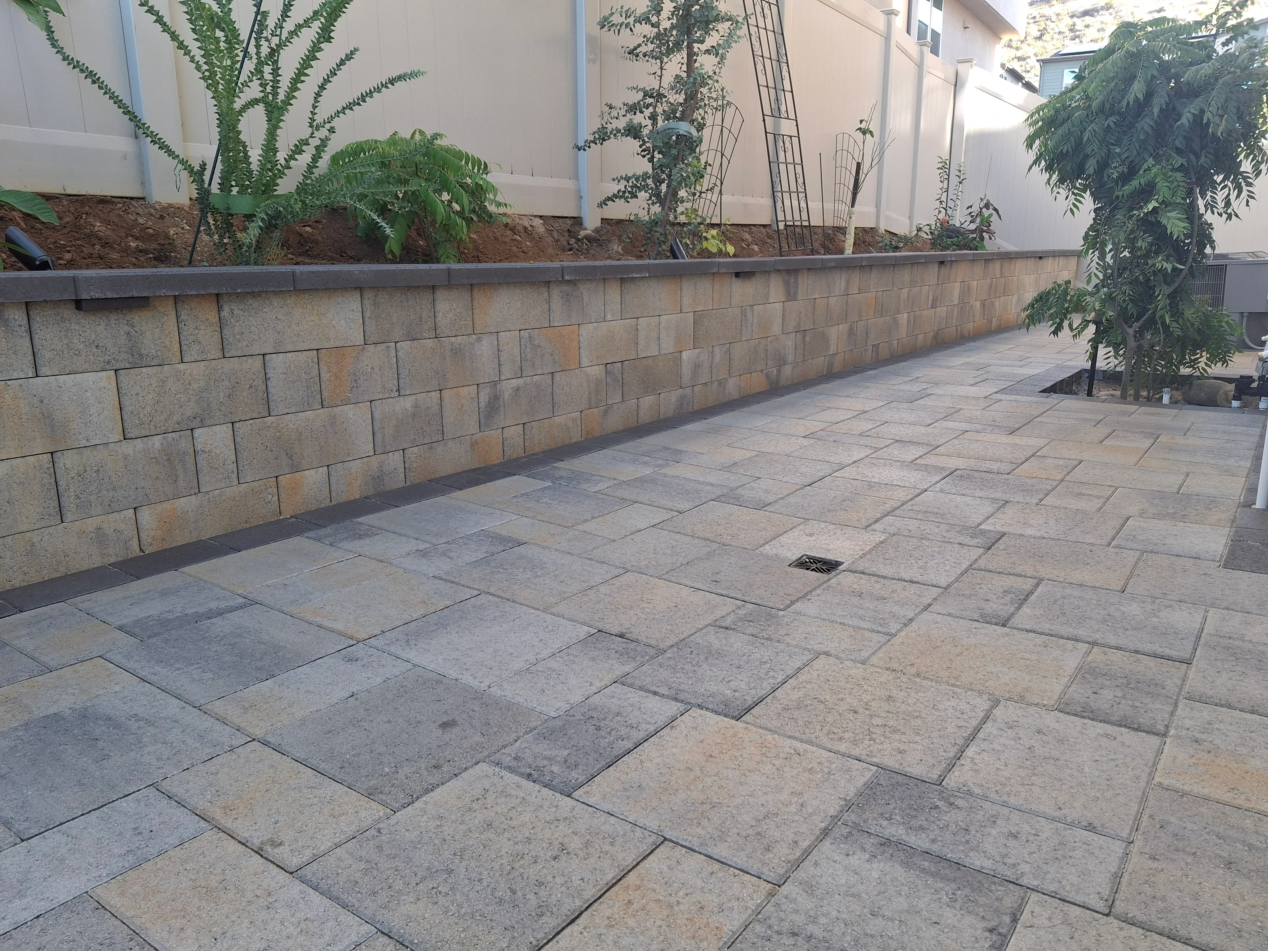 Concrete paver patio with running bond pattern and stacked block retaining wall