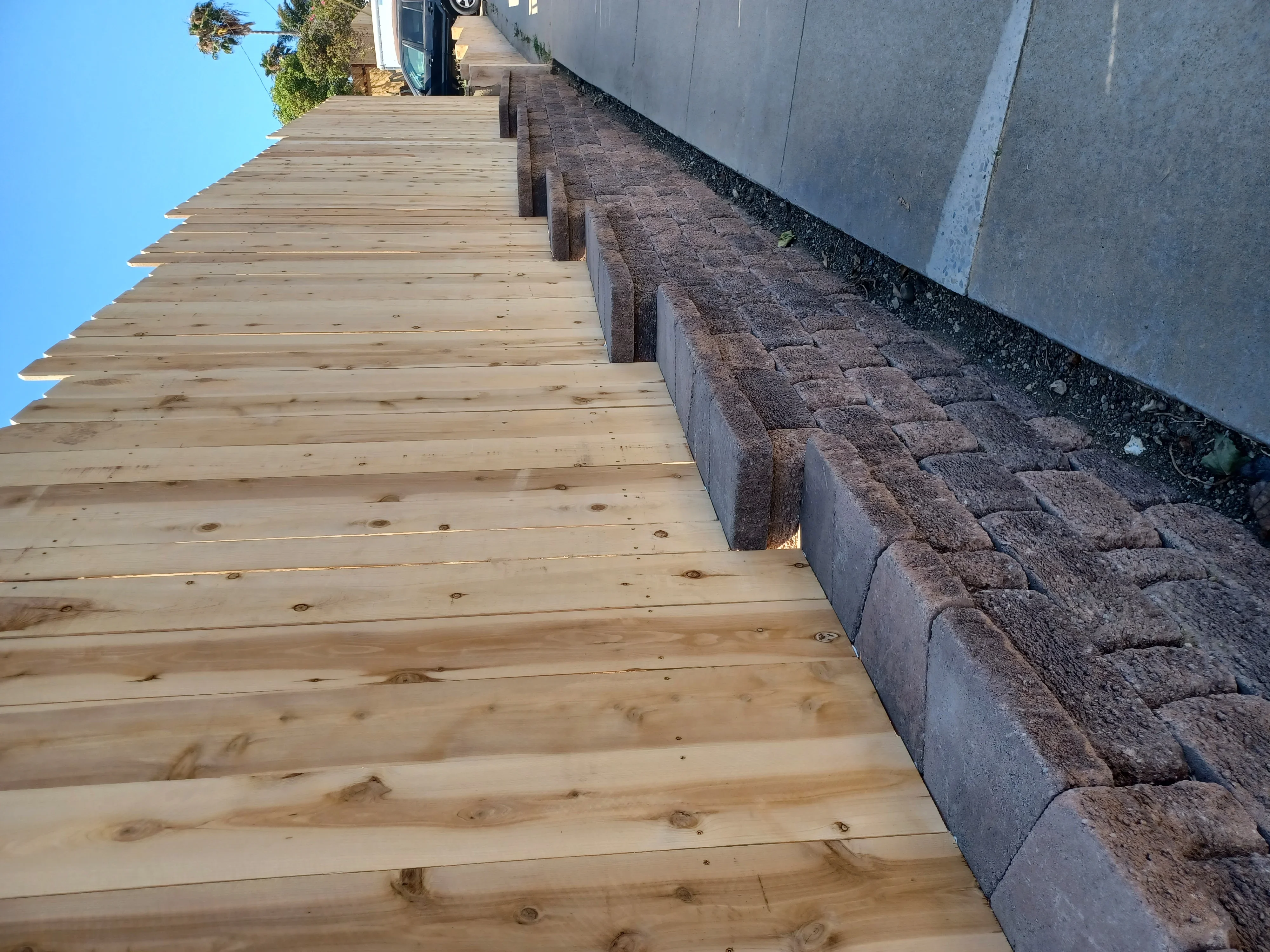 Newly installed wooden deck boards next to timber retaining wall