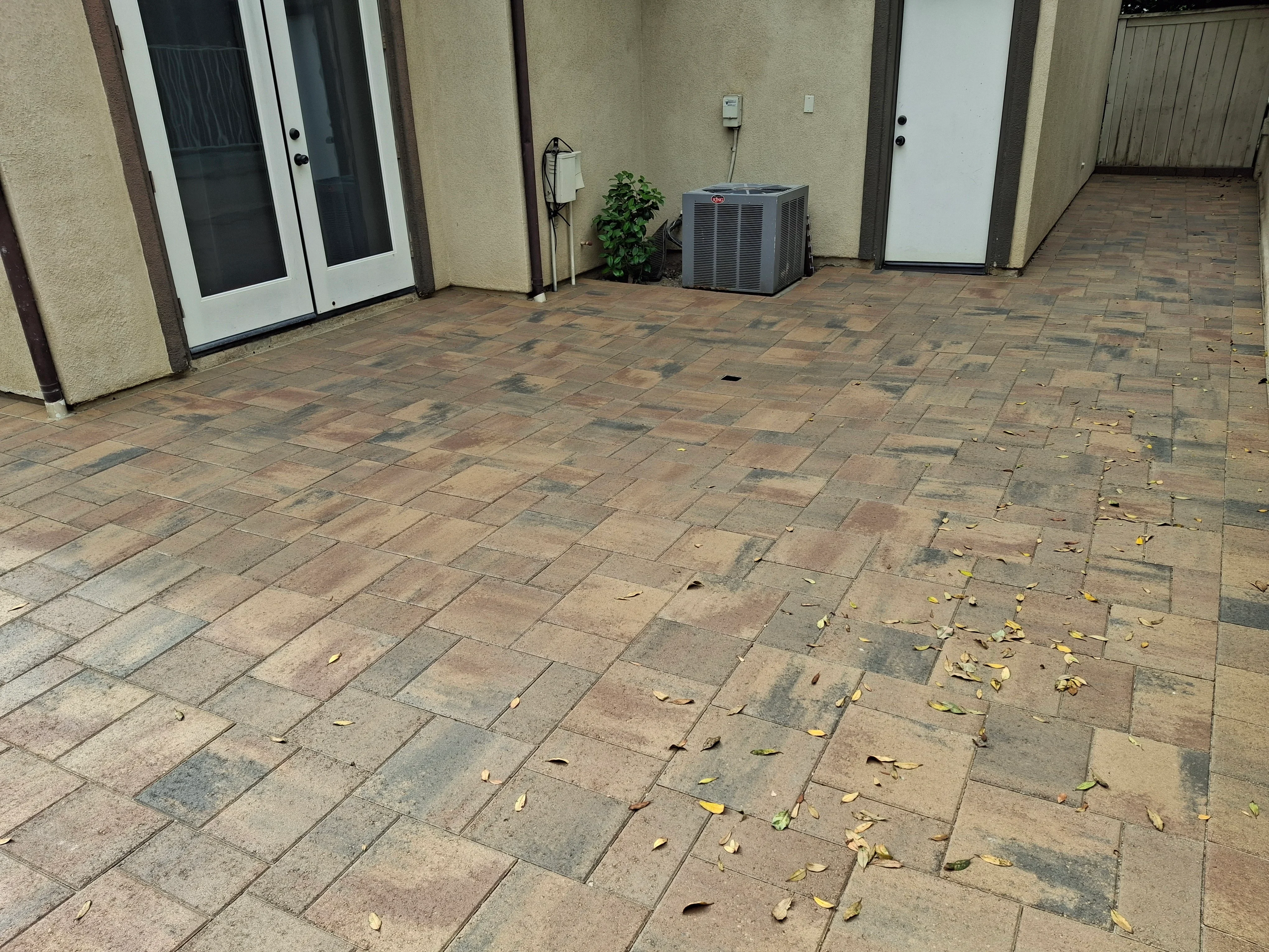 Multi-colored clay paver patio with running bond pattern and proper drainage grading