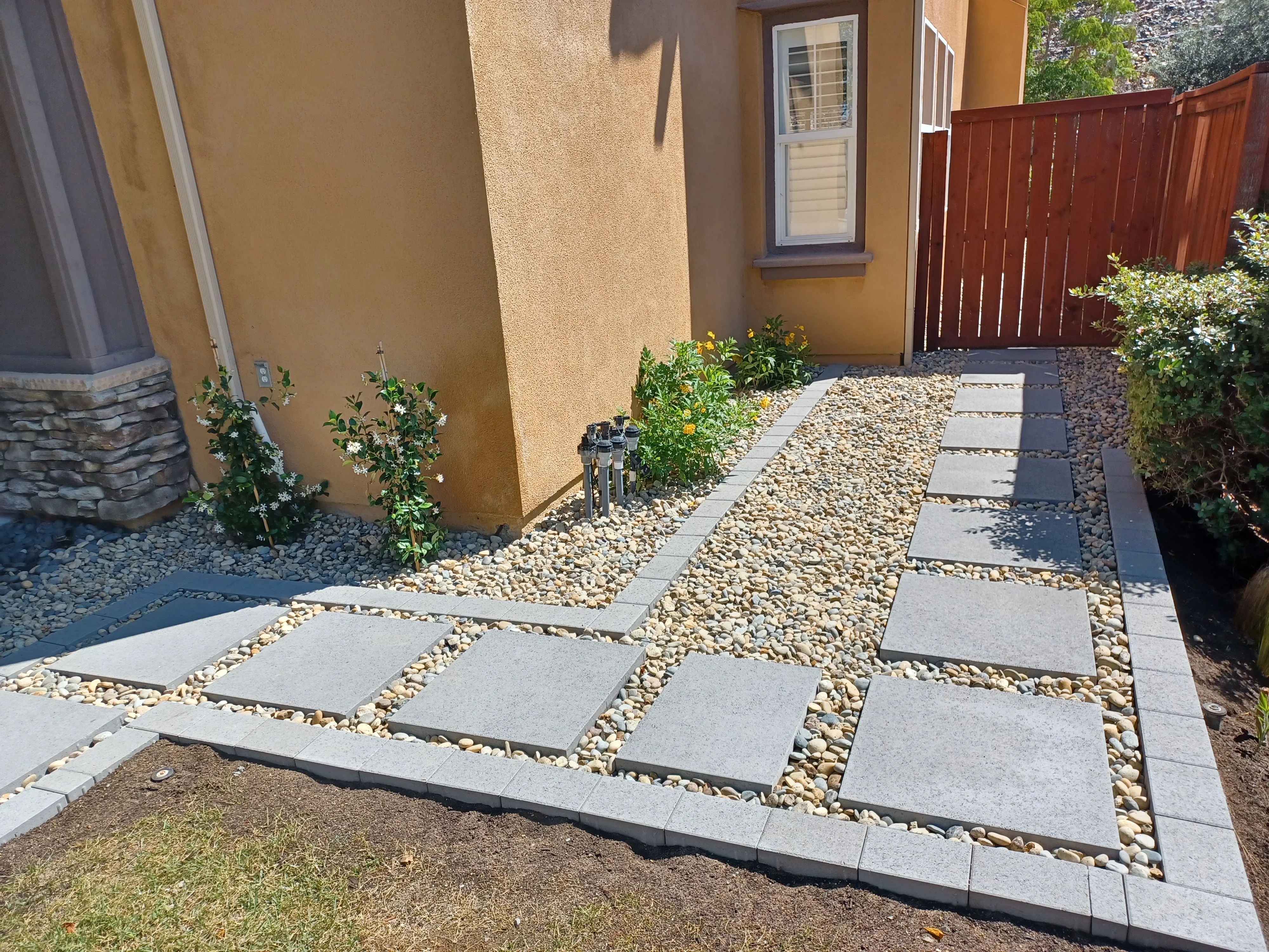 Concrete stepping stones with river rock infill and landscape edging in side yard