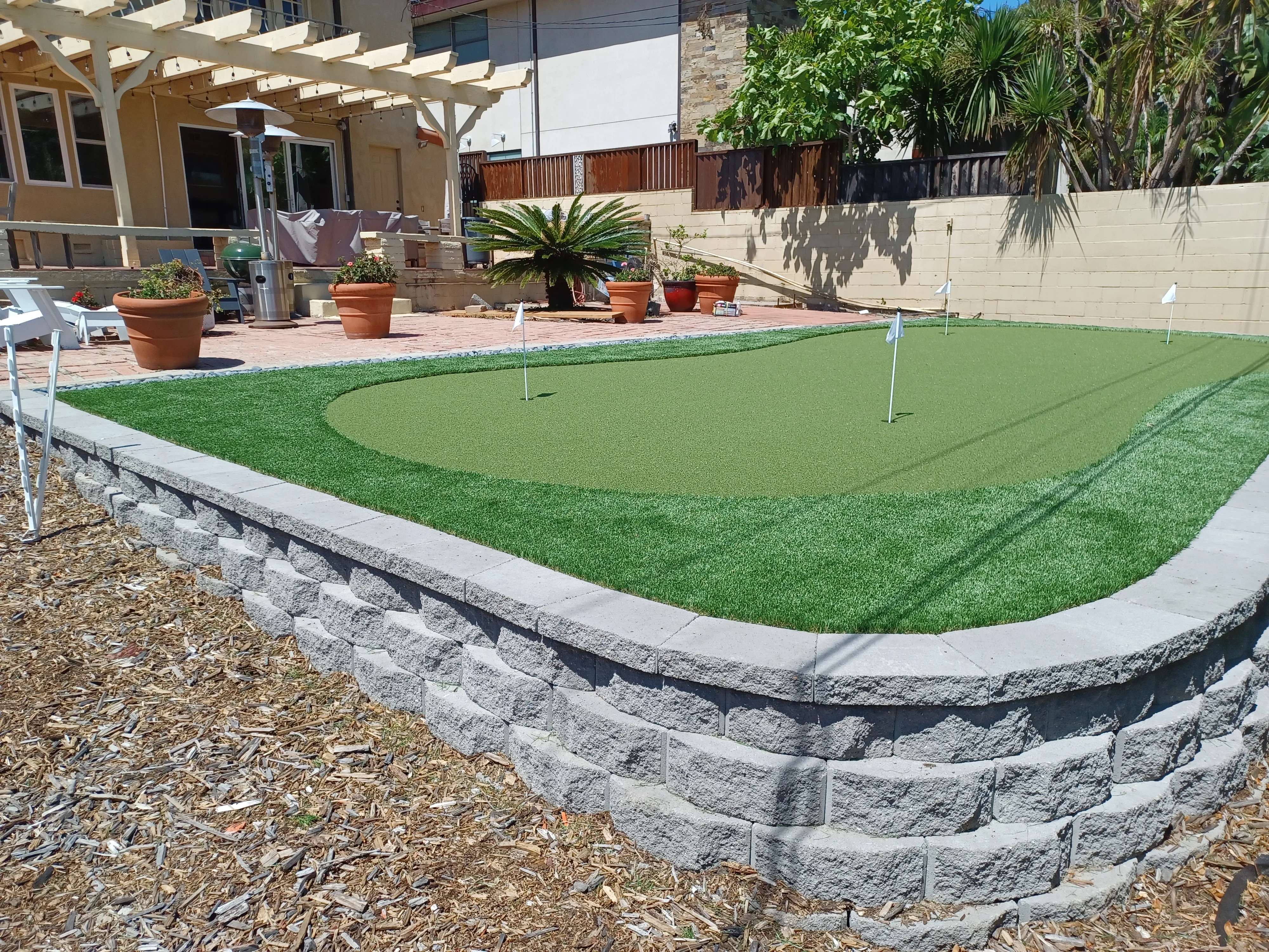 Synthetic putting green with curved granite retaining wall and concrete edging