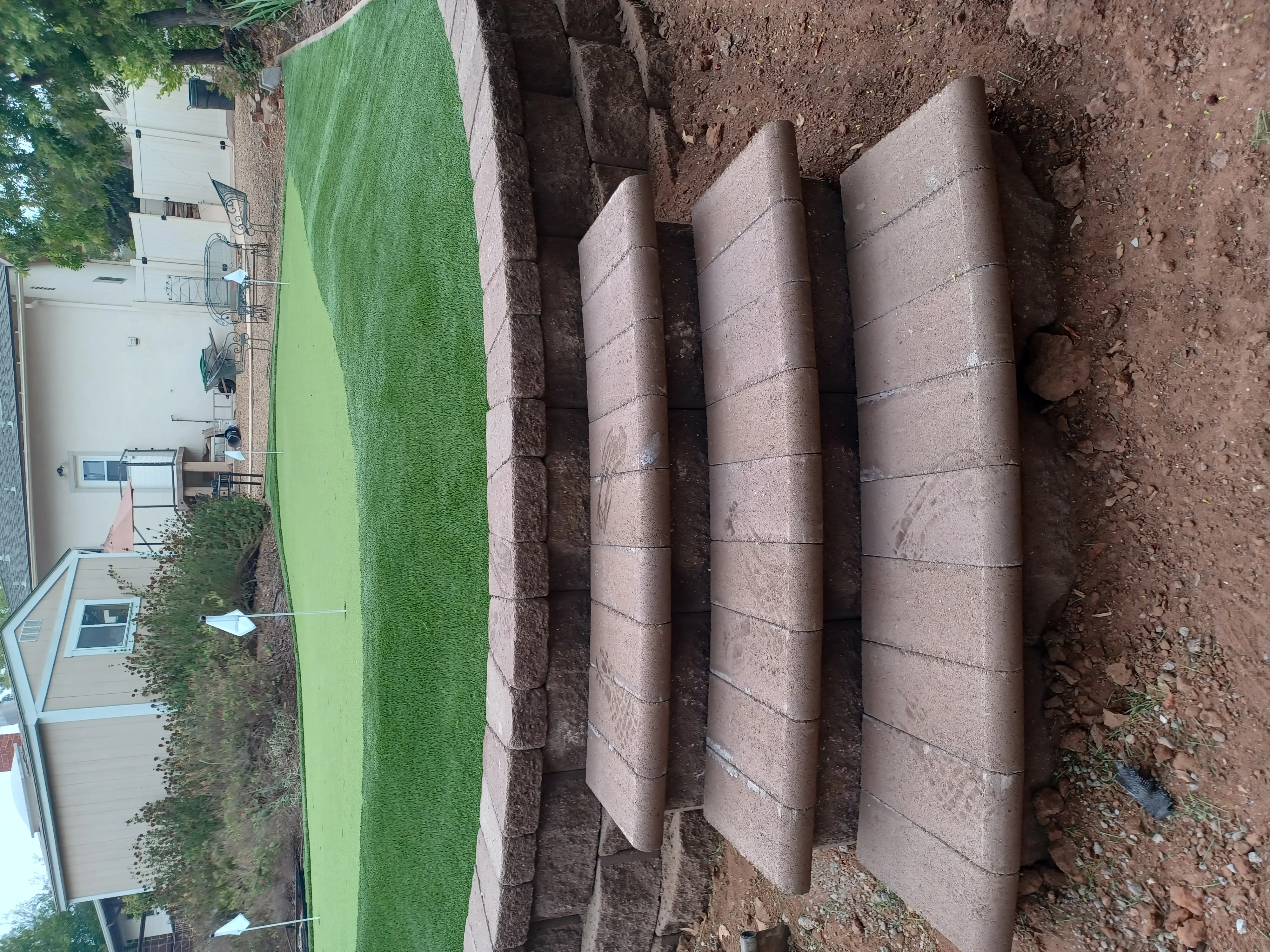Three cylindrical concrete retaining wall sections with horizontal joints installed on sloped terrain