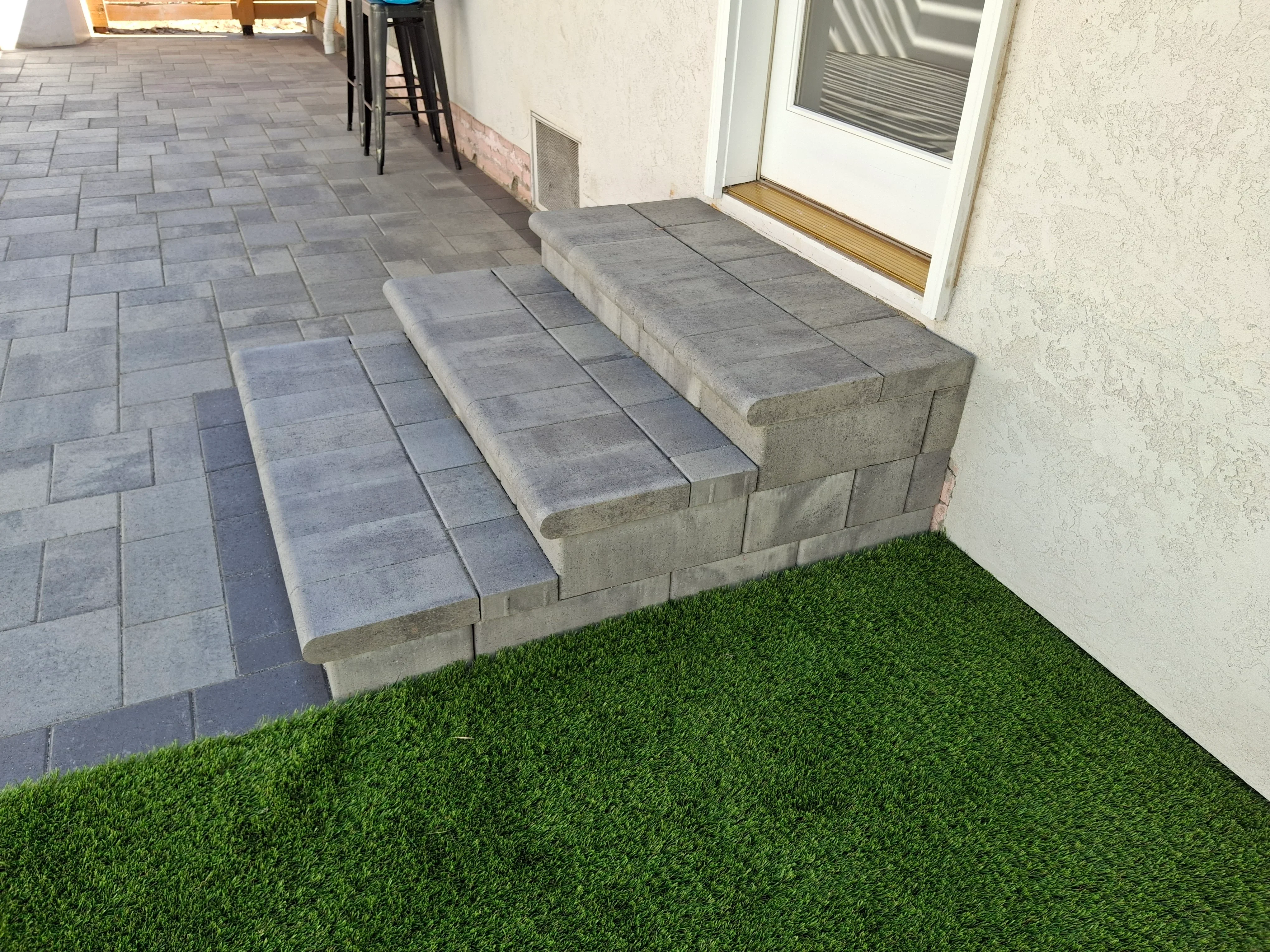 Concrete steps with bullnose edges and gray paver patio, artificial turf at base