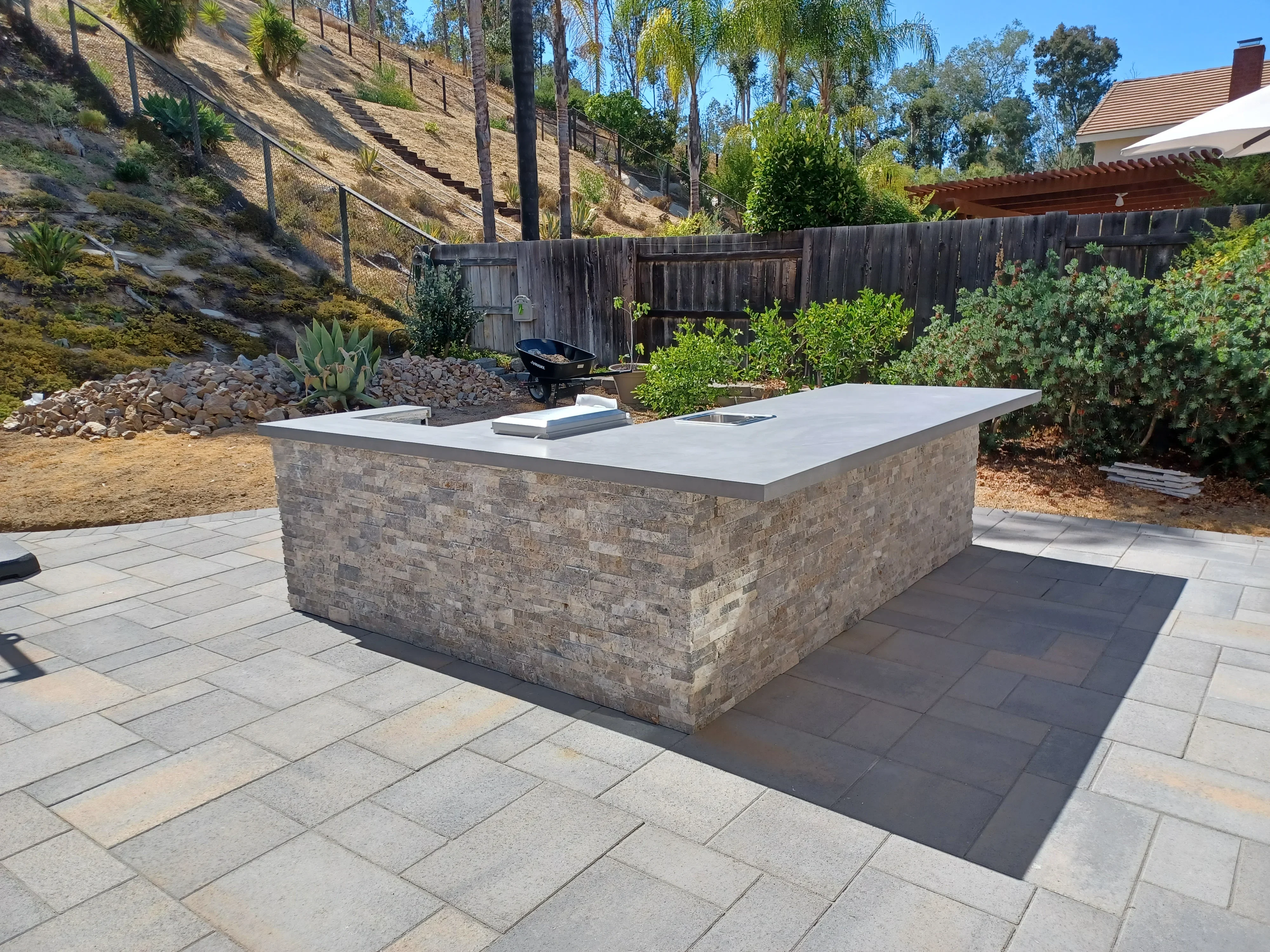 Stone veneer kitchen island with white countertop on multi-tone paver patio