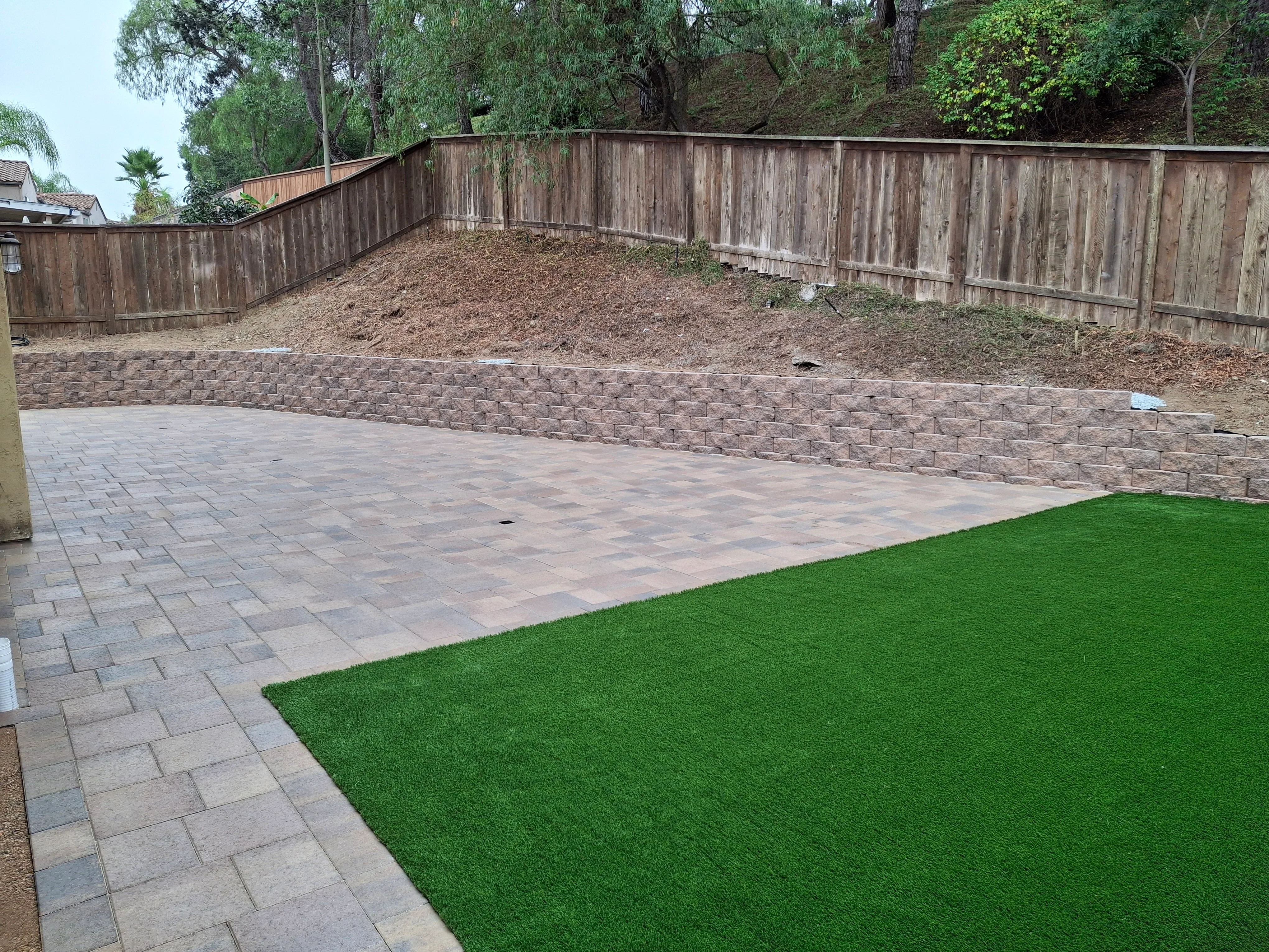 Permeable paver patio with segmental retaining wall and synthetic turf installation