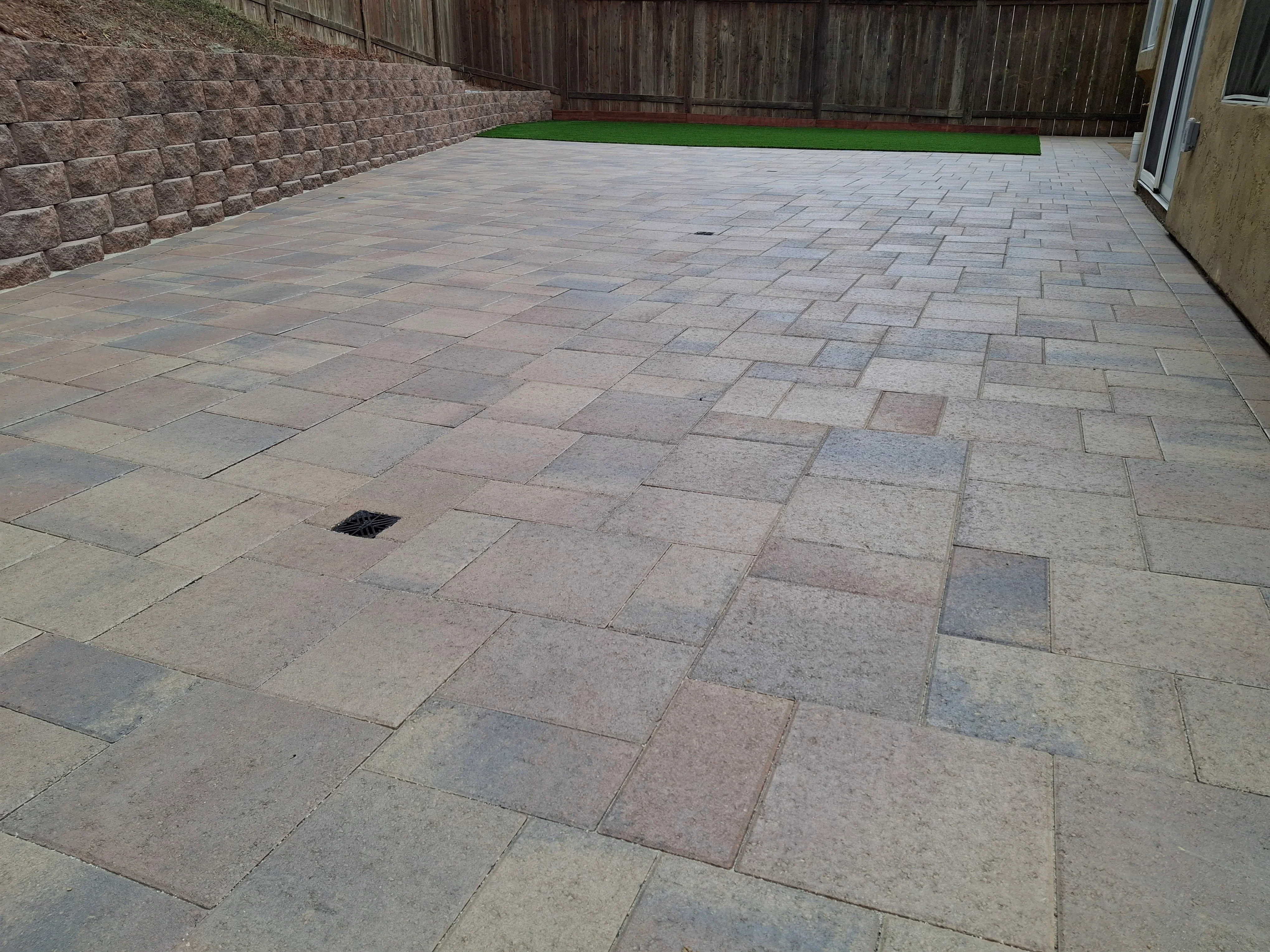Permeable concrete paver patio with herringbone pattern and retaining wall