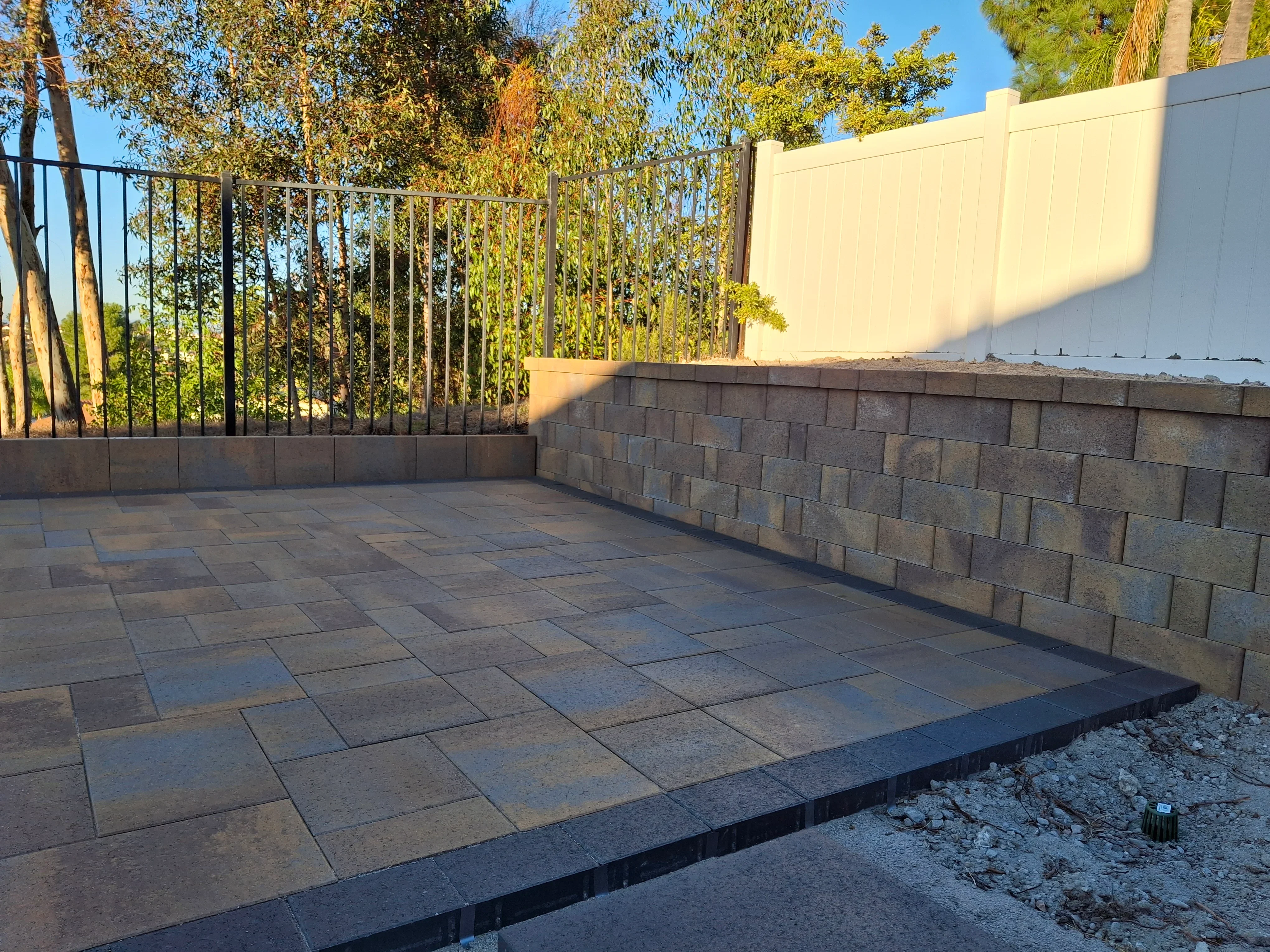 Gray concrete pavers in running bond pattern with segmental retaining wall and metal railing