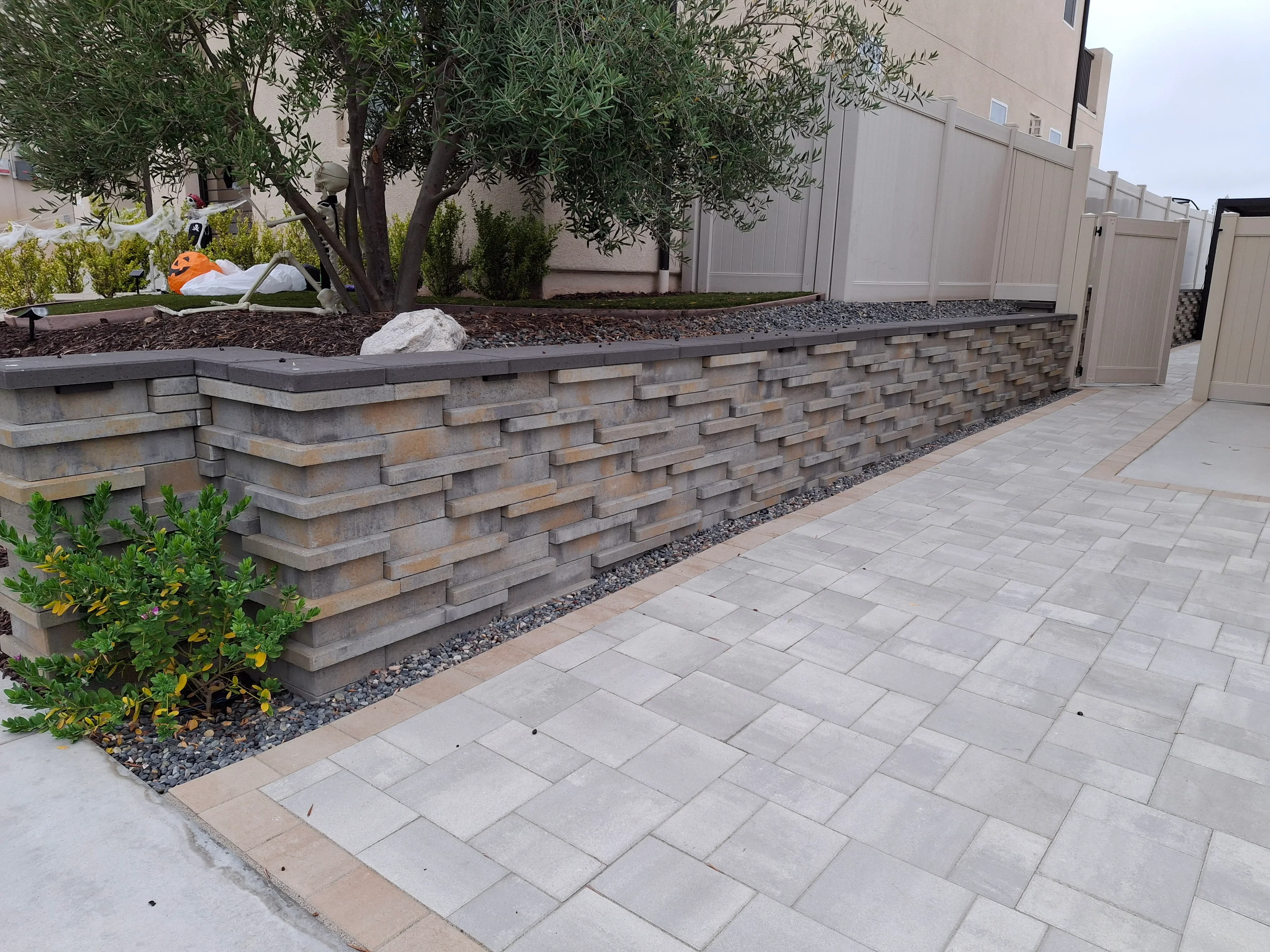 Stacked stone retaining wall with concrete pavers and landscape planting bed