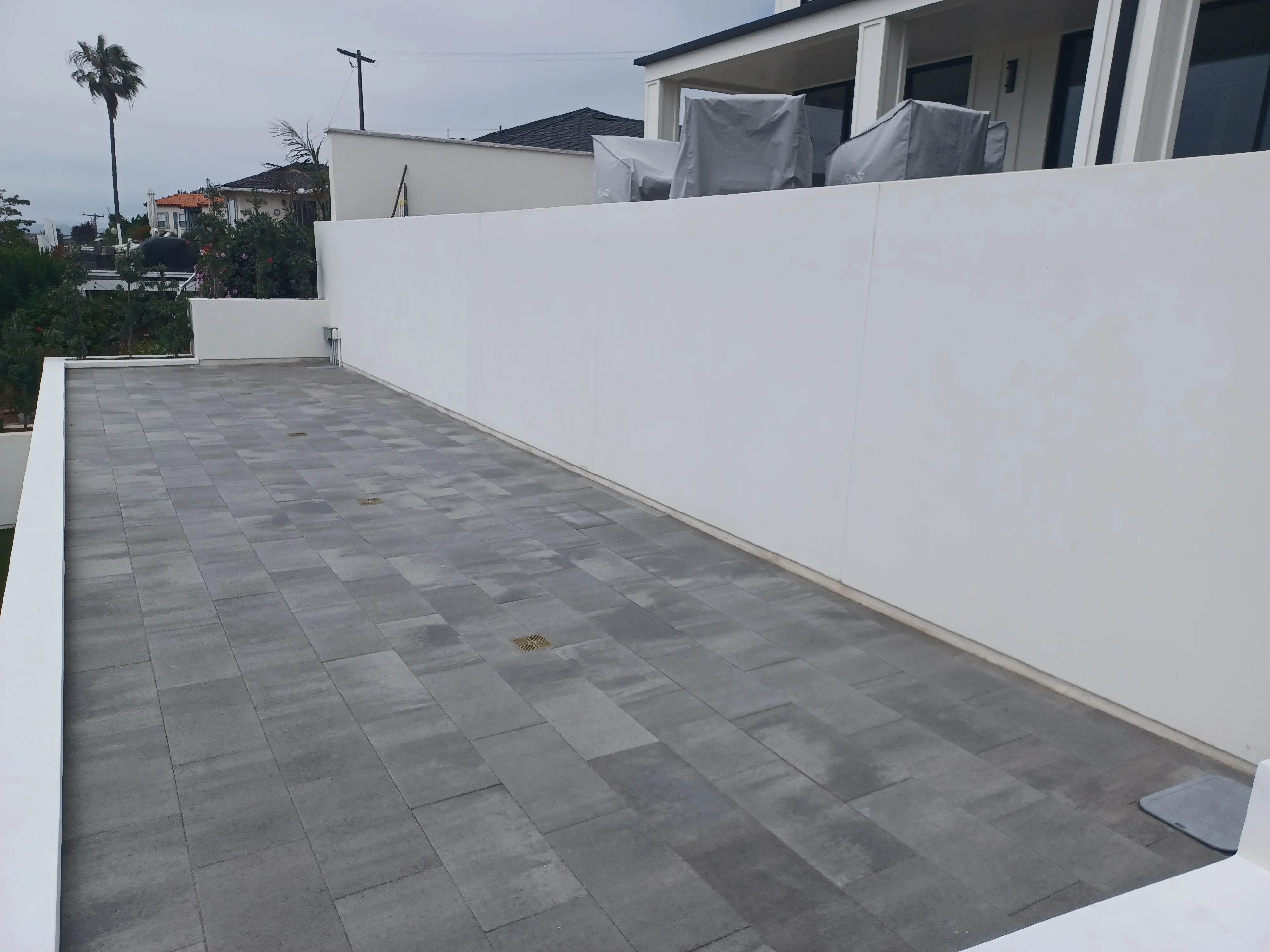Gray concrete pavers in running bond pattern on residential patio with white retaining wall