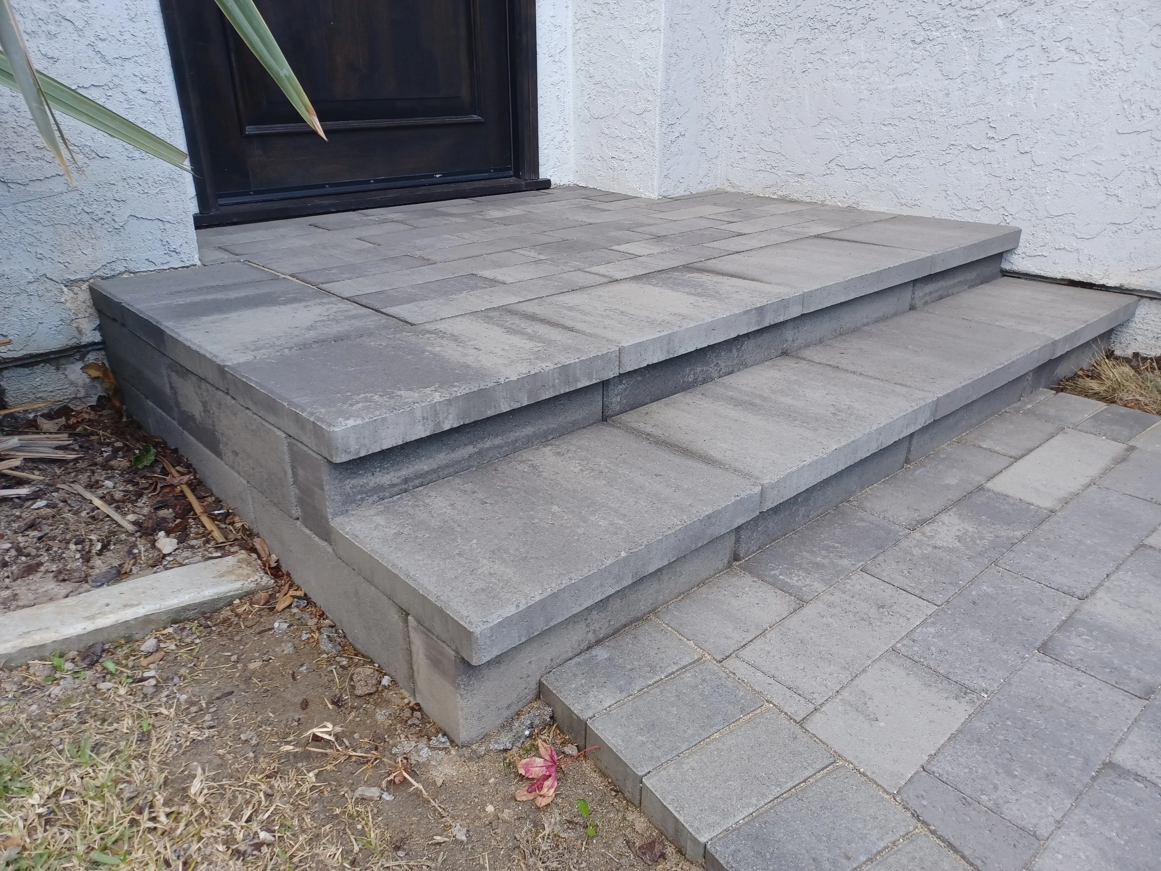 Gray concrete paver entry platform with tiered steps and concrete base blocks