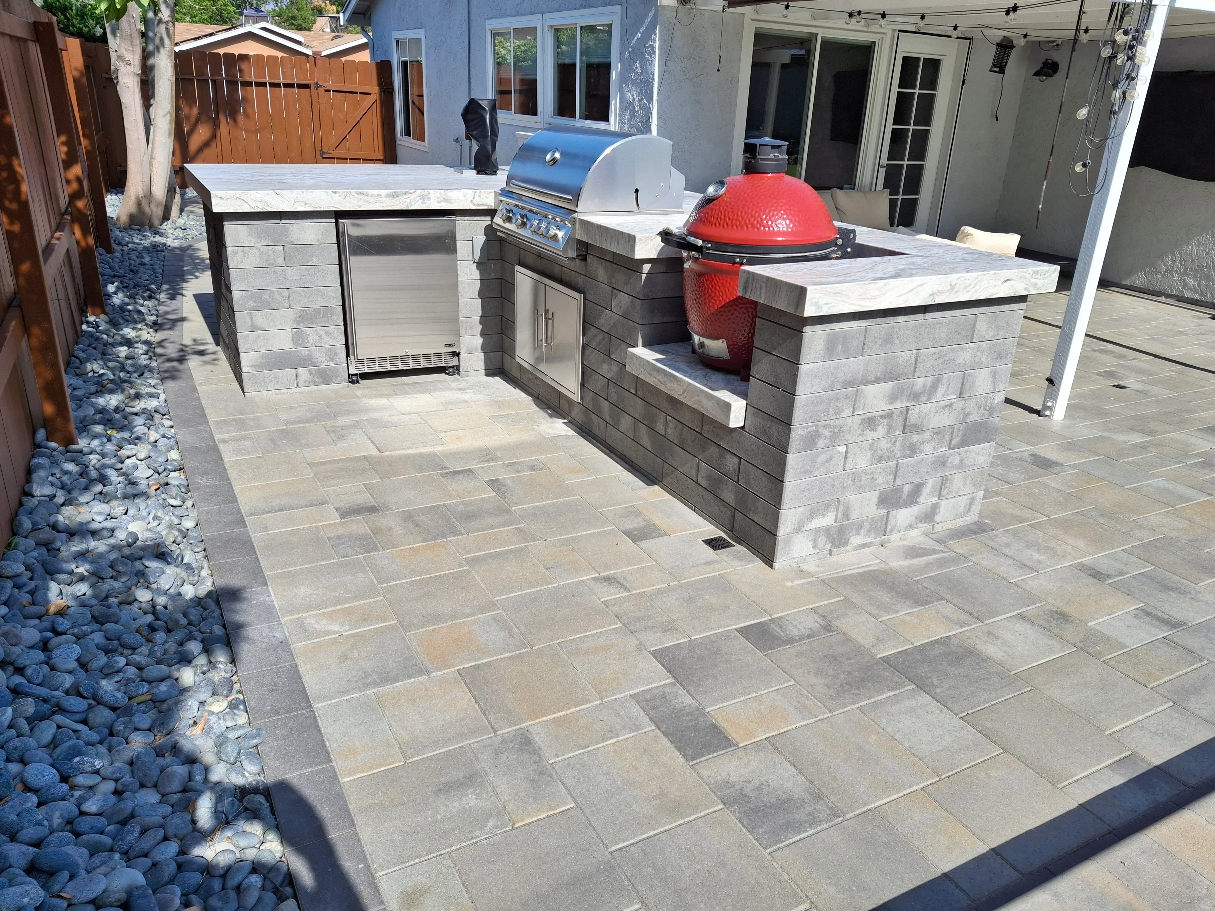 Concrete paver patio with built-in outdoor kitchen, grill, and red smoker