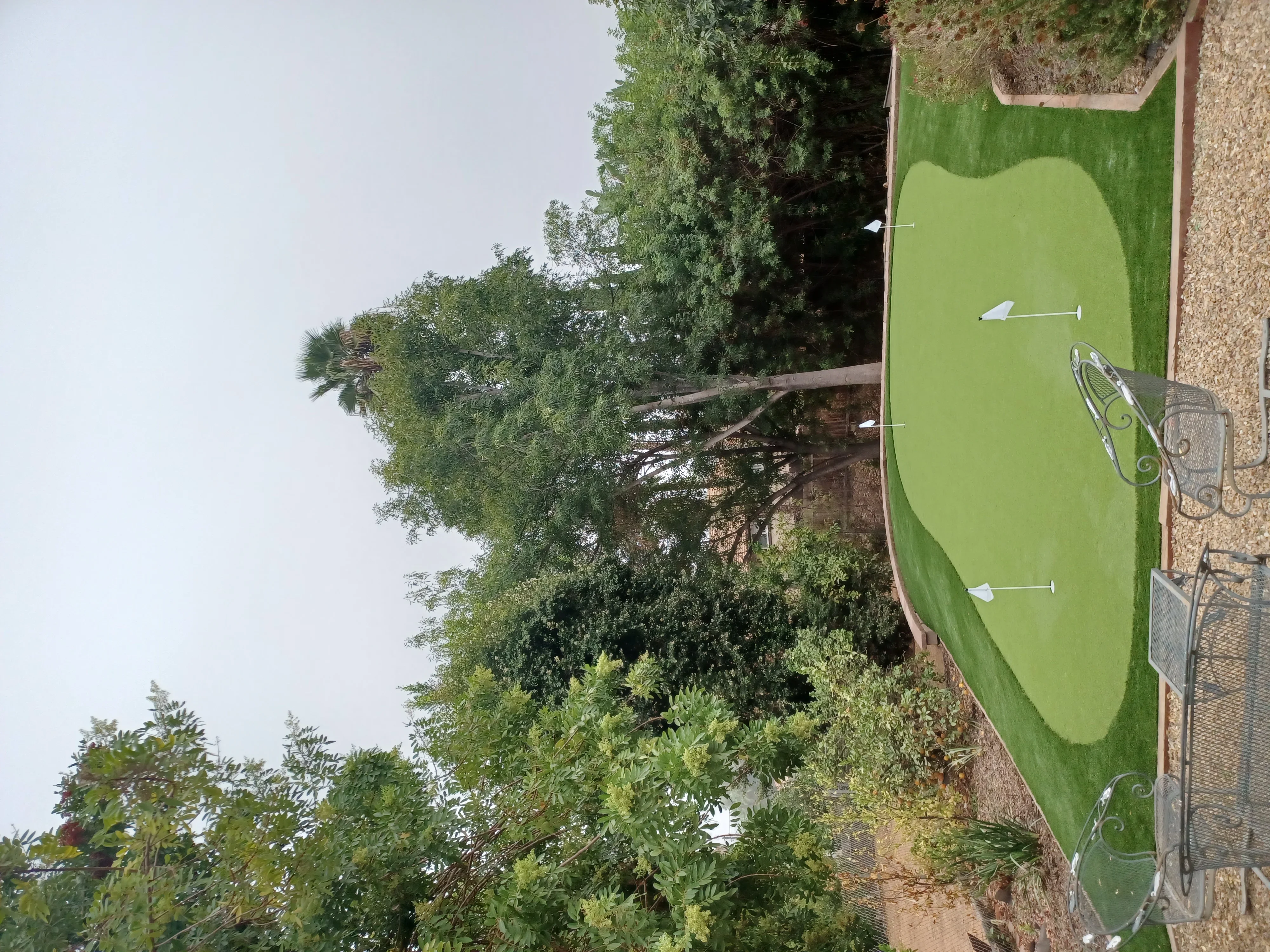 Synthetic putting green with contoured turf, cup holes, and stone border edging