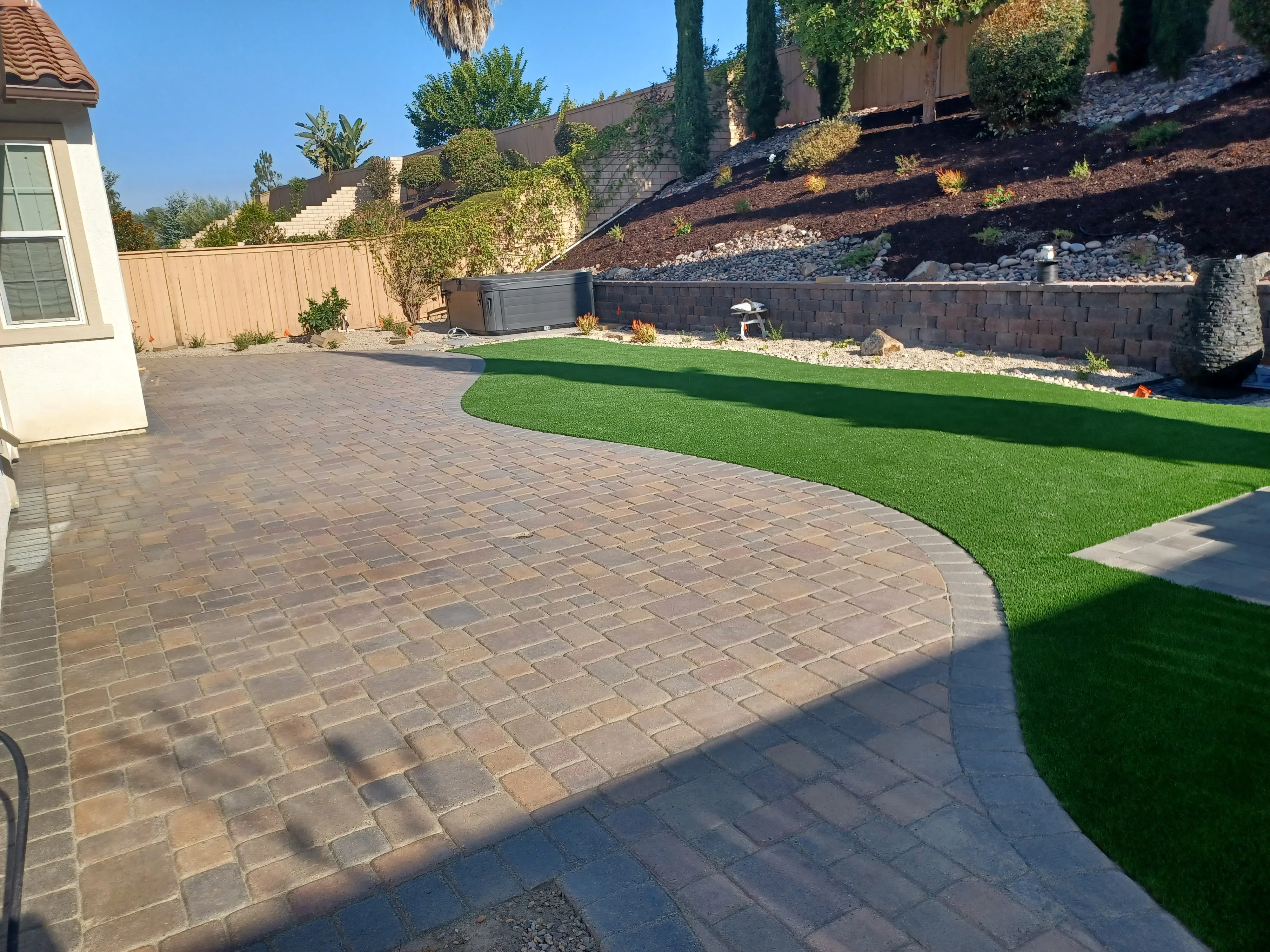 Permeable paver patio with synthetic turf, retaining wall, and landscape edging