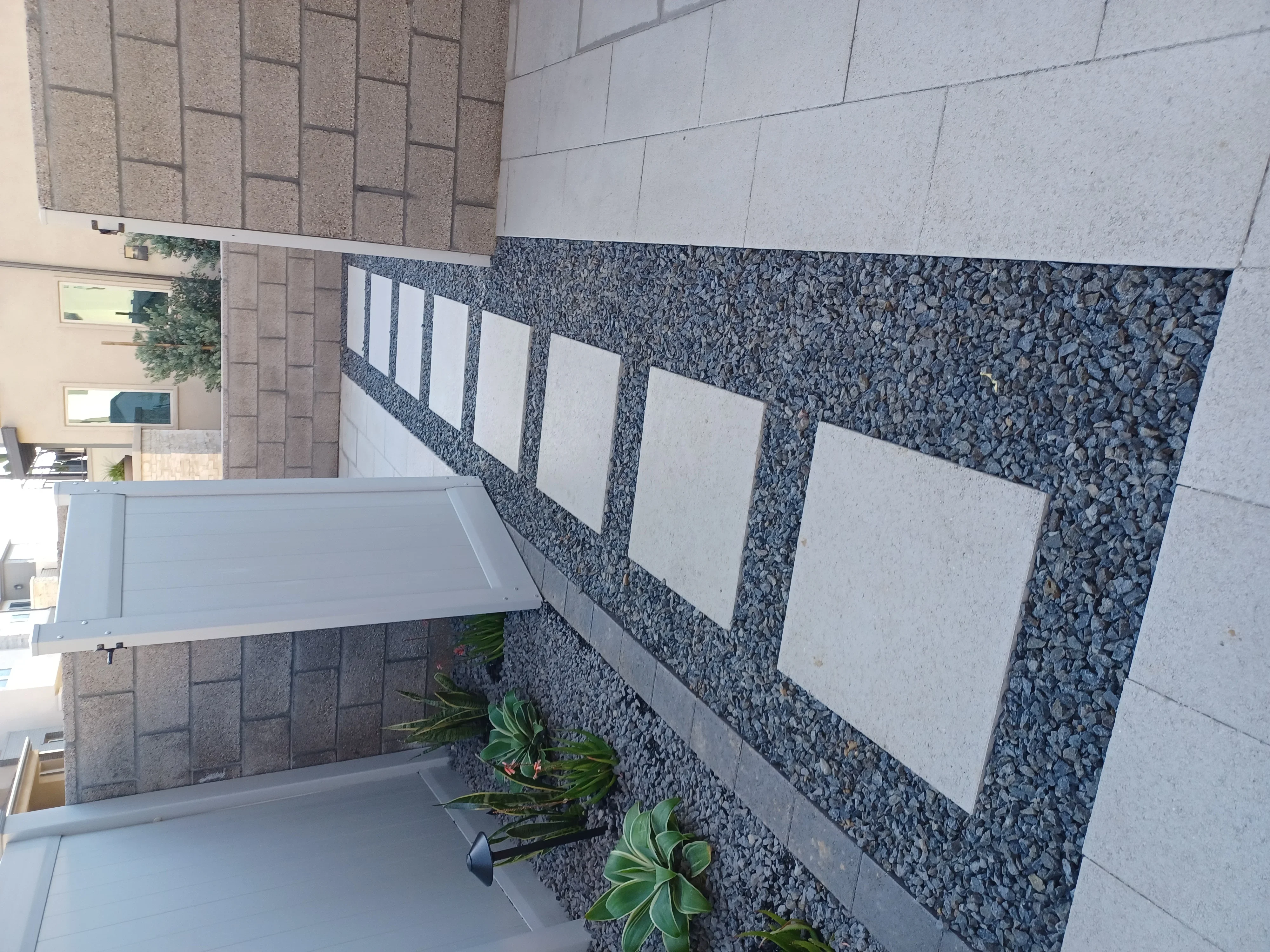 Concrete pavers with decorative stone borders and white accent panels in geometric pattern