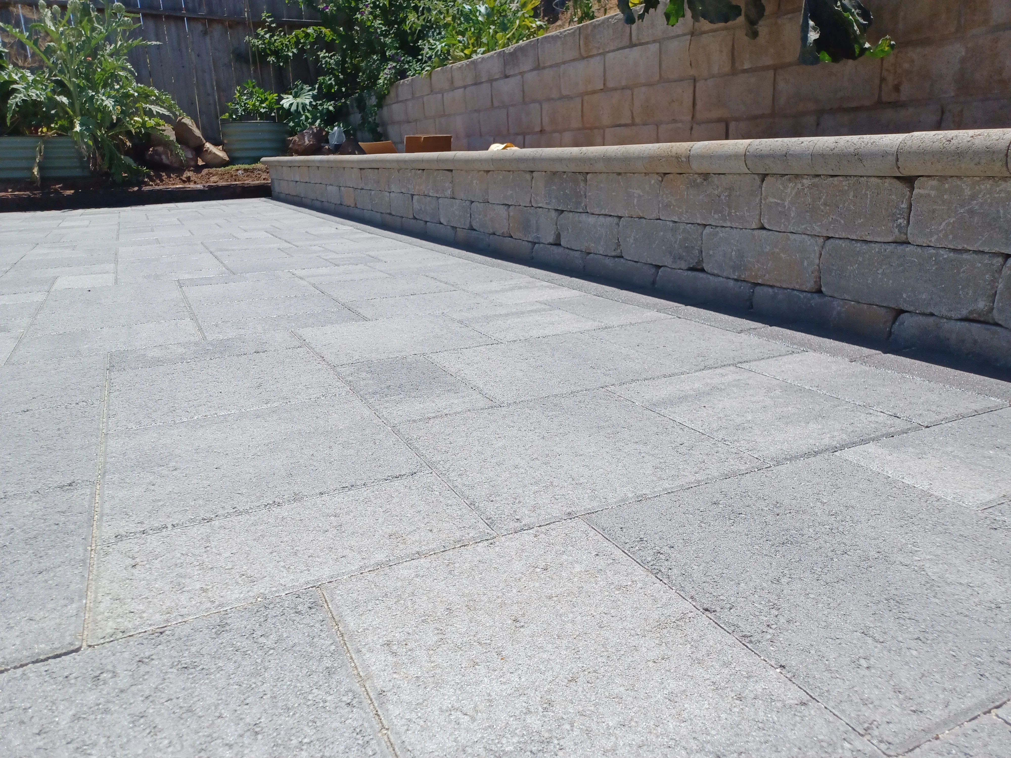 Concrete paver patio with uniform grout lines and segmental concrete block retaining wall