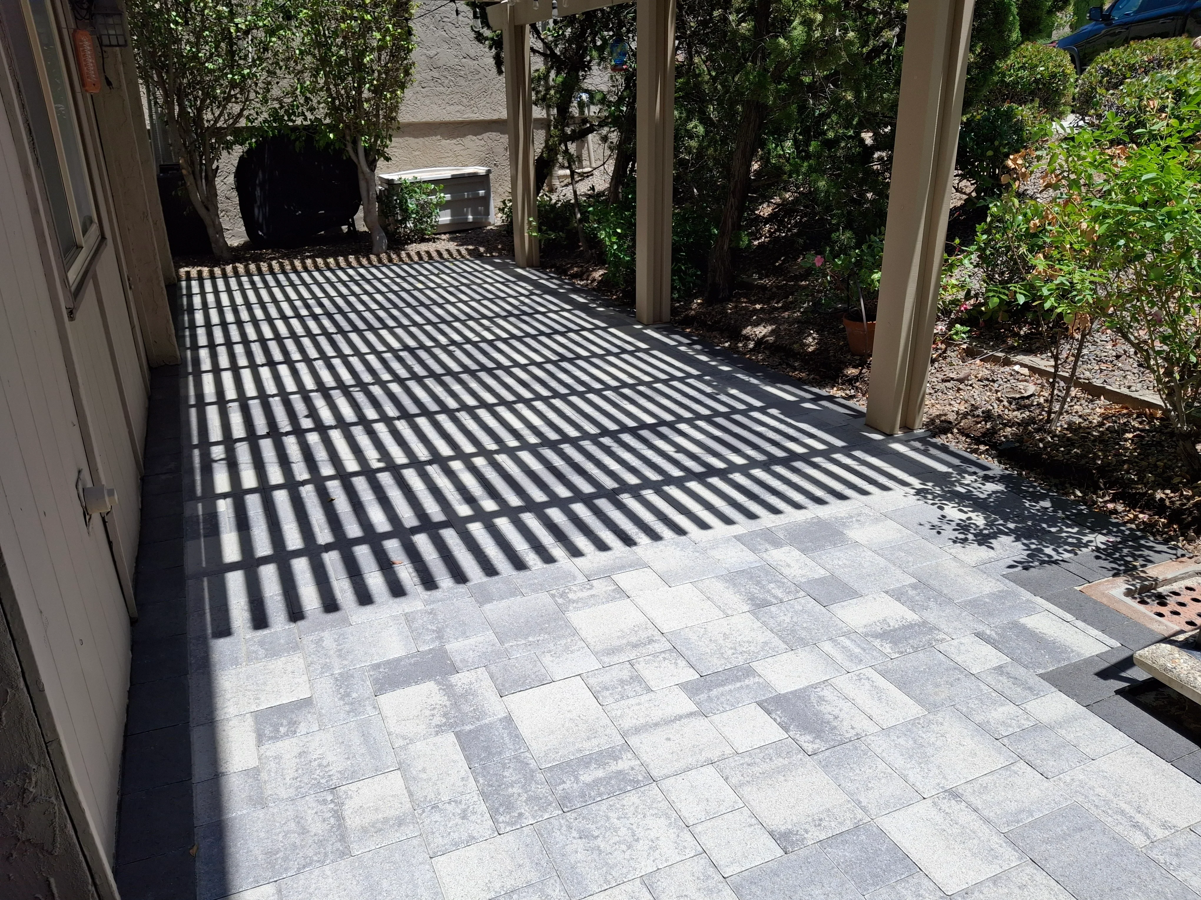 Herringbone paver patio with pergola shade structure and landscape plantings