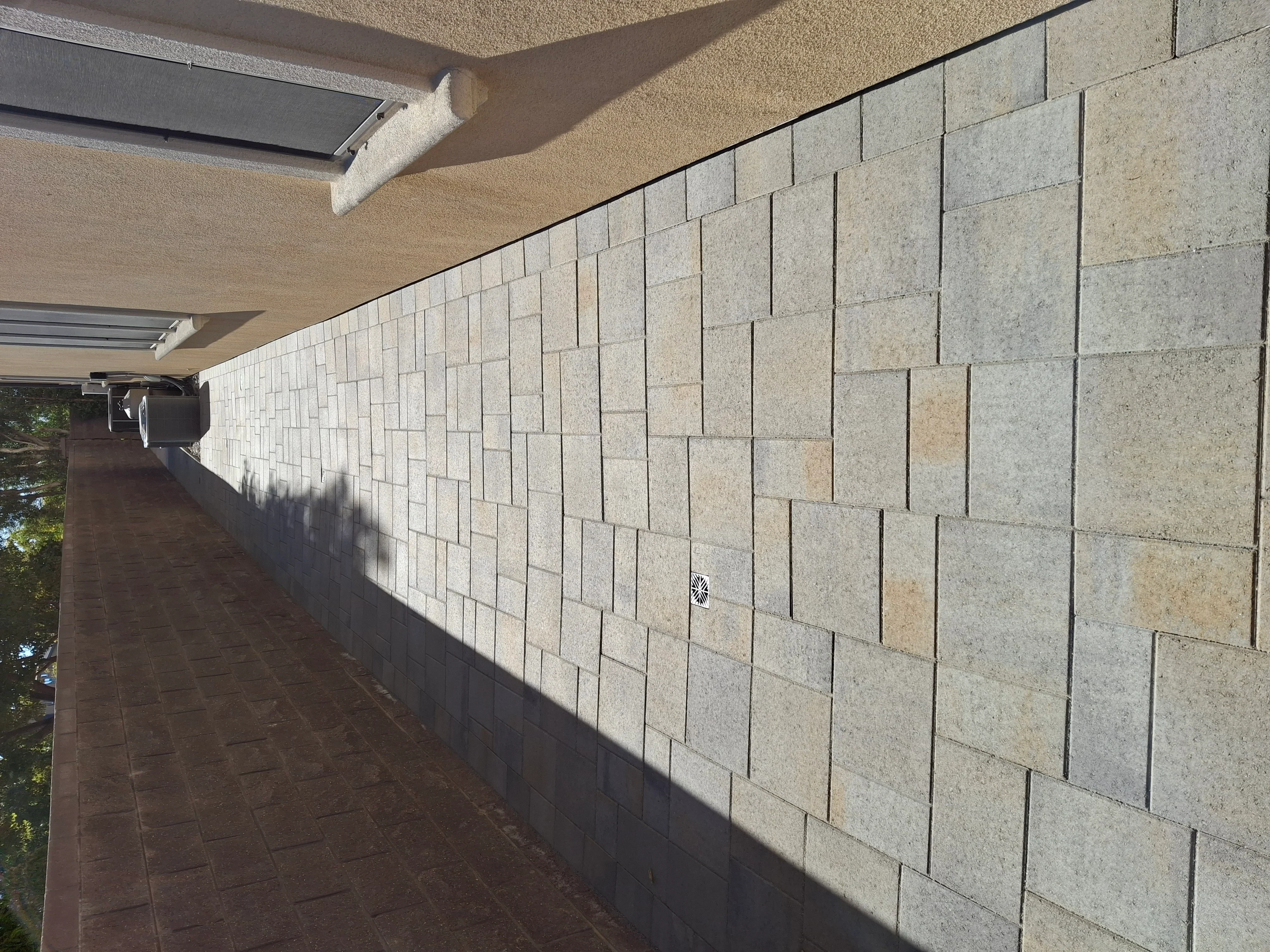 Concrete block retaining wall with running bond pattern along patio area