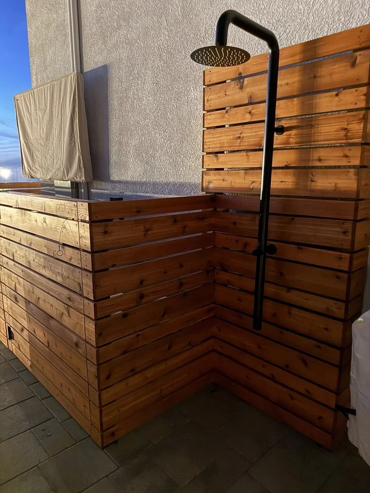 Cedar slat outdoor shower enclosure with black steel pipe frame and rainfall showerhead