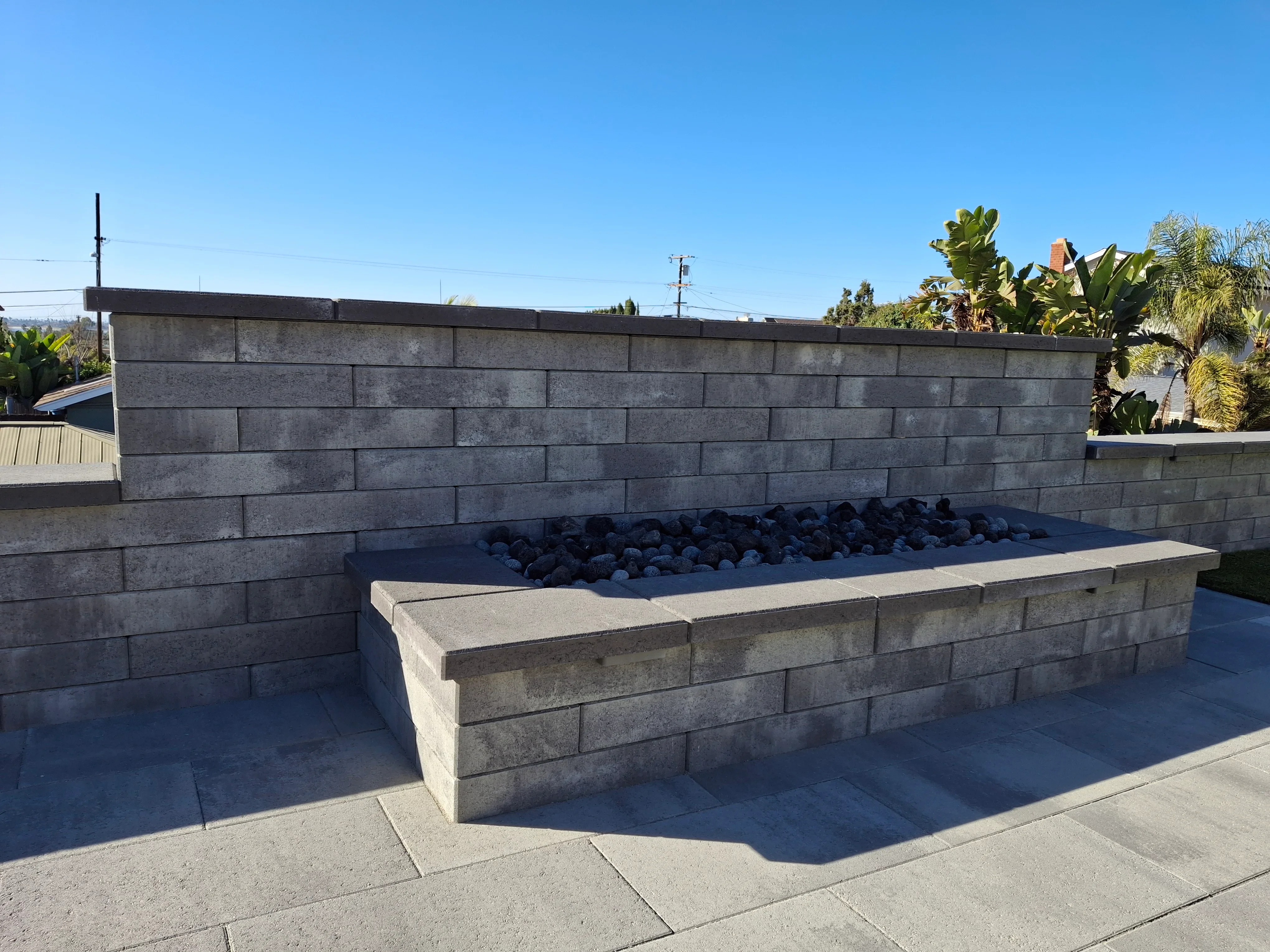 Concrete block fire pit with lava rock and matching retaining wall on patio