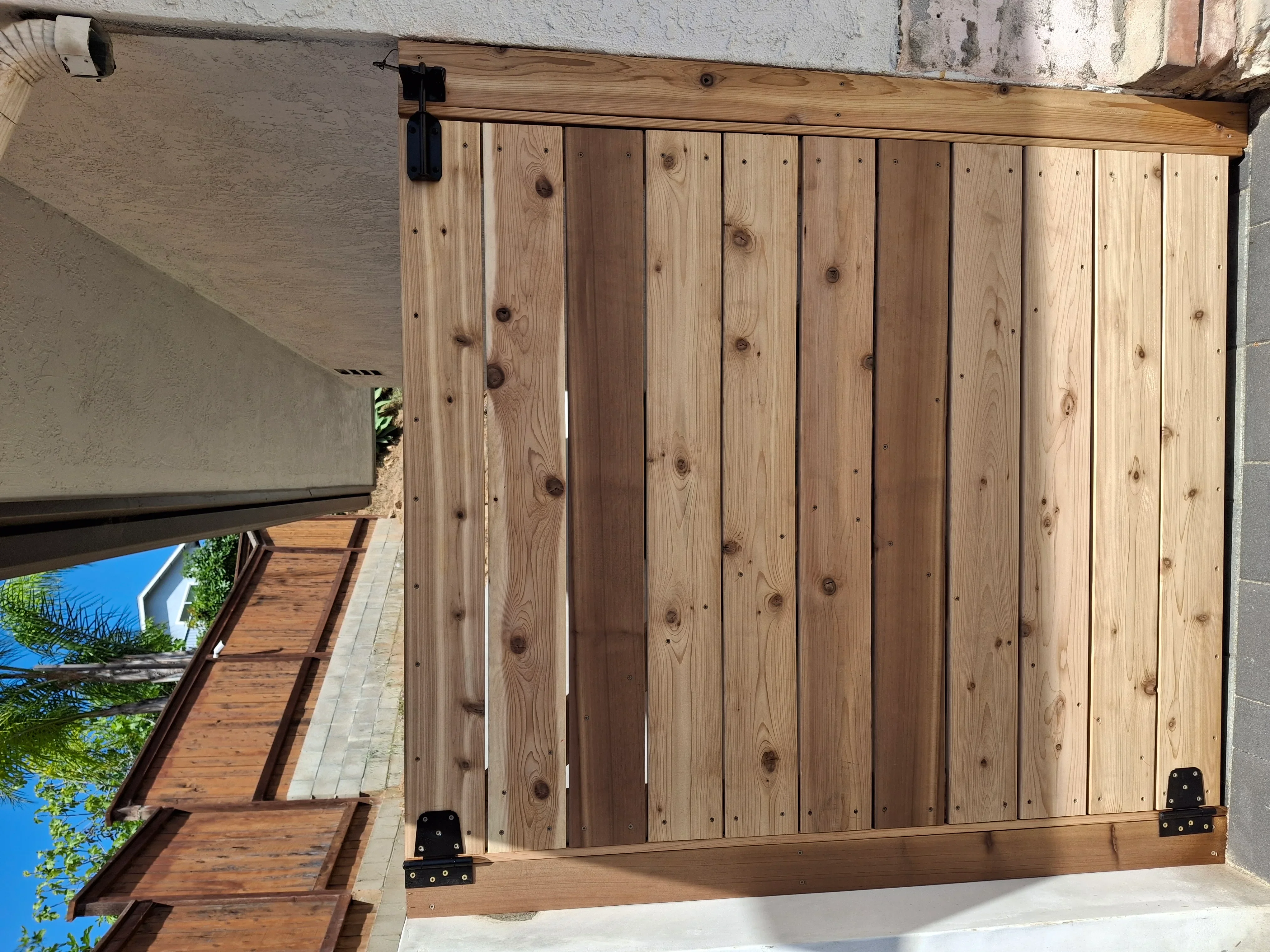 Vertical pine barn door with black hardware and sliding track mounted on stucco wall
