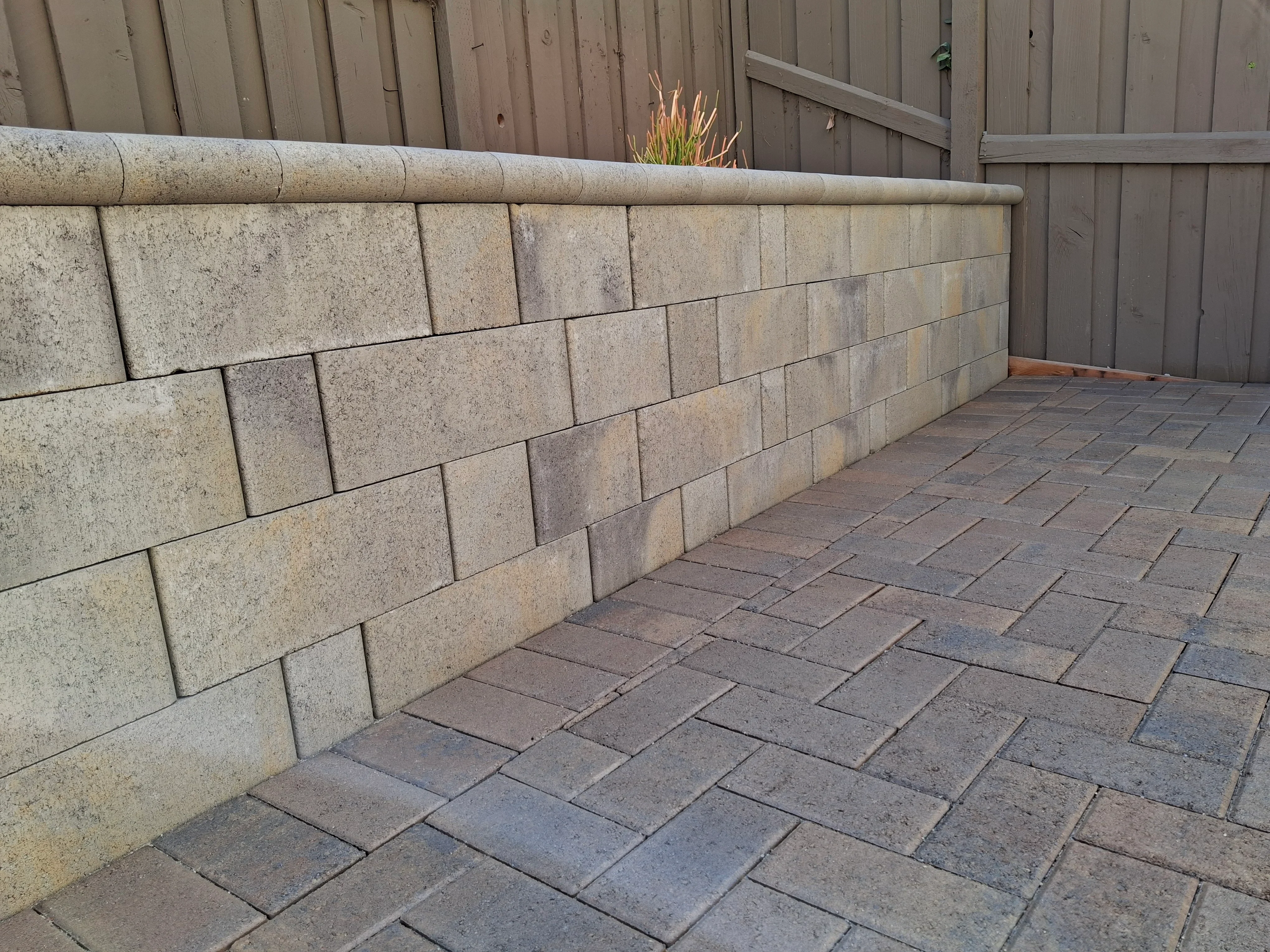 Concrete block retaining wall with rounded cap and running bond paver patio