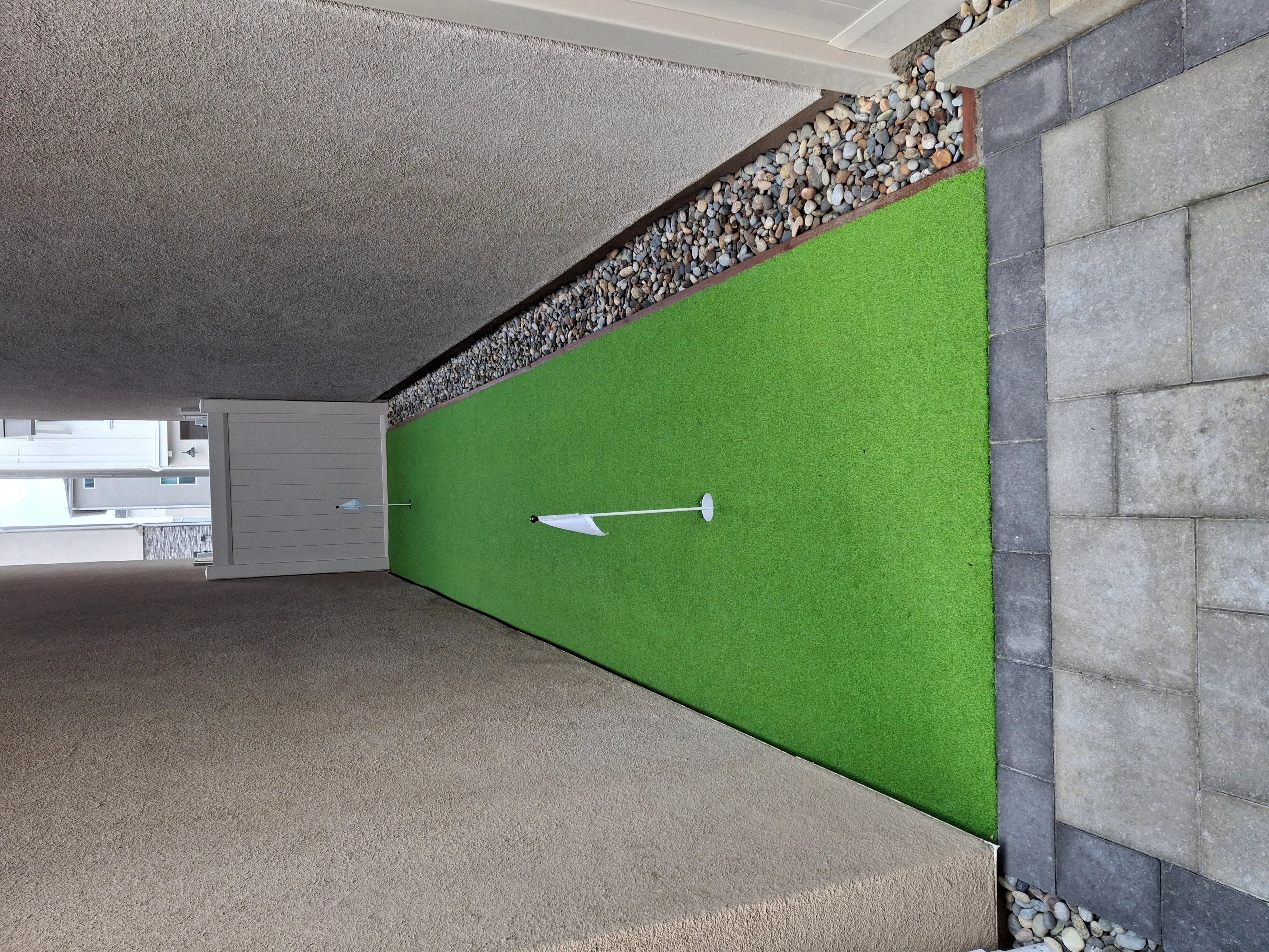 Synthetic turf wall with concrete pavers, river rock border, and block retaining wall installation