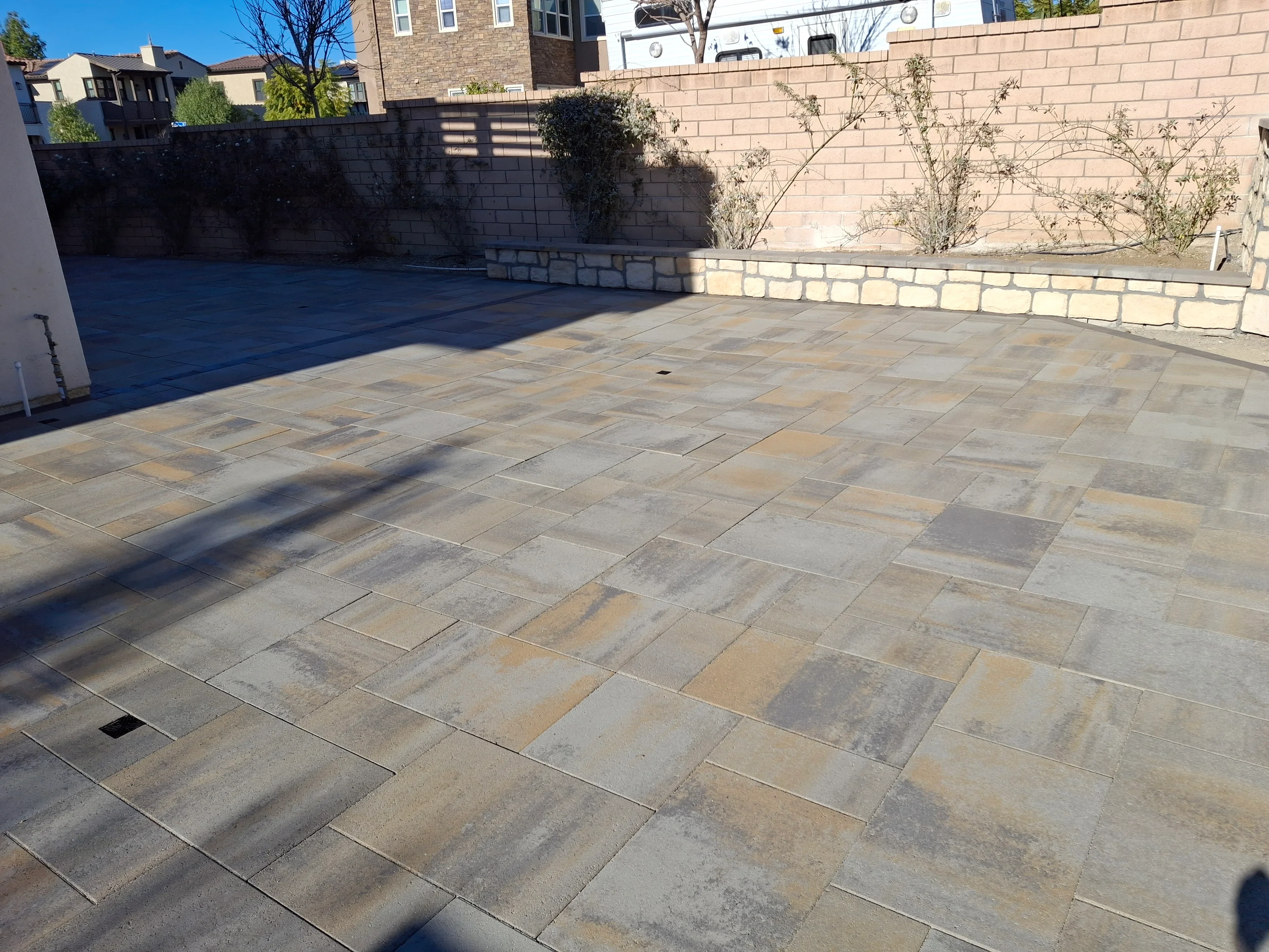 Natural stone patio with mixed gray and tan pavers in running bond pattern, concrete retaining walls