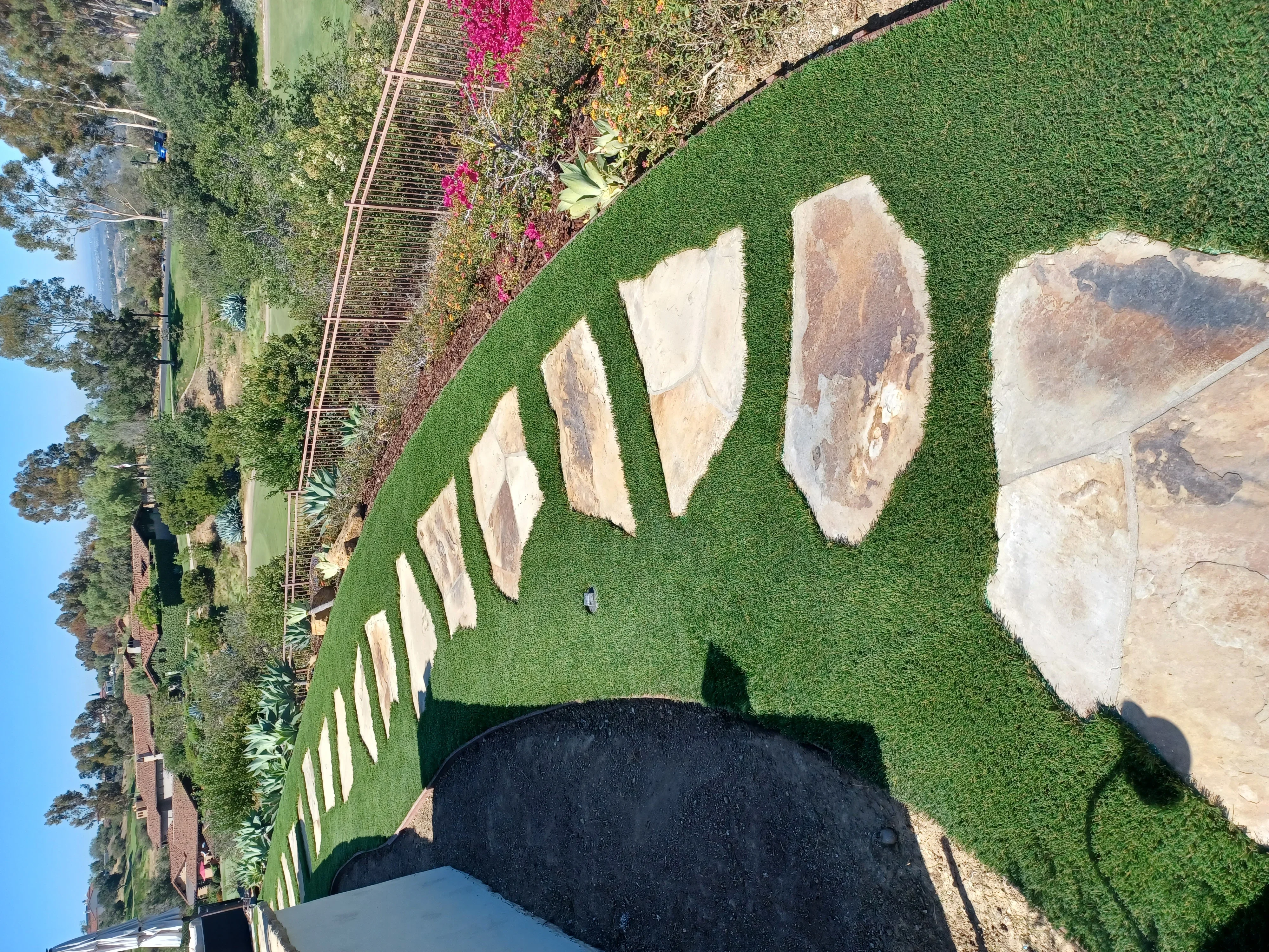 Travertine pavers installed in lawn with natural stone edging and landscape borders