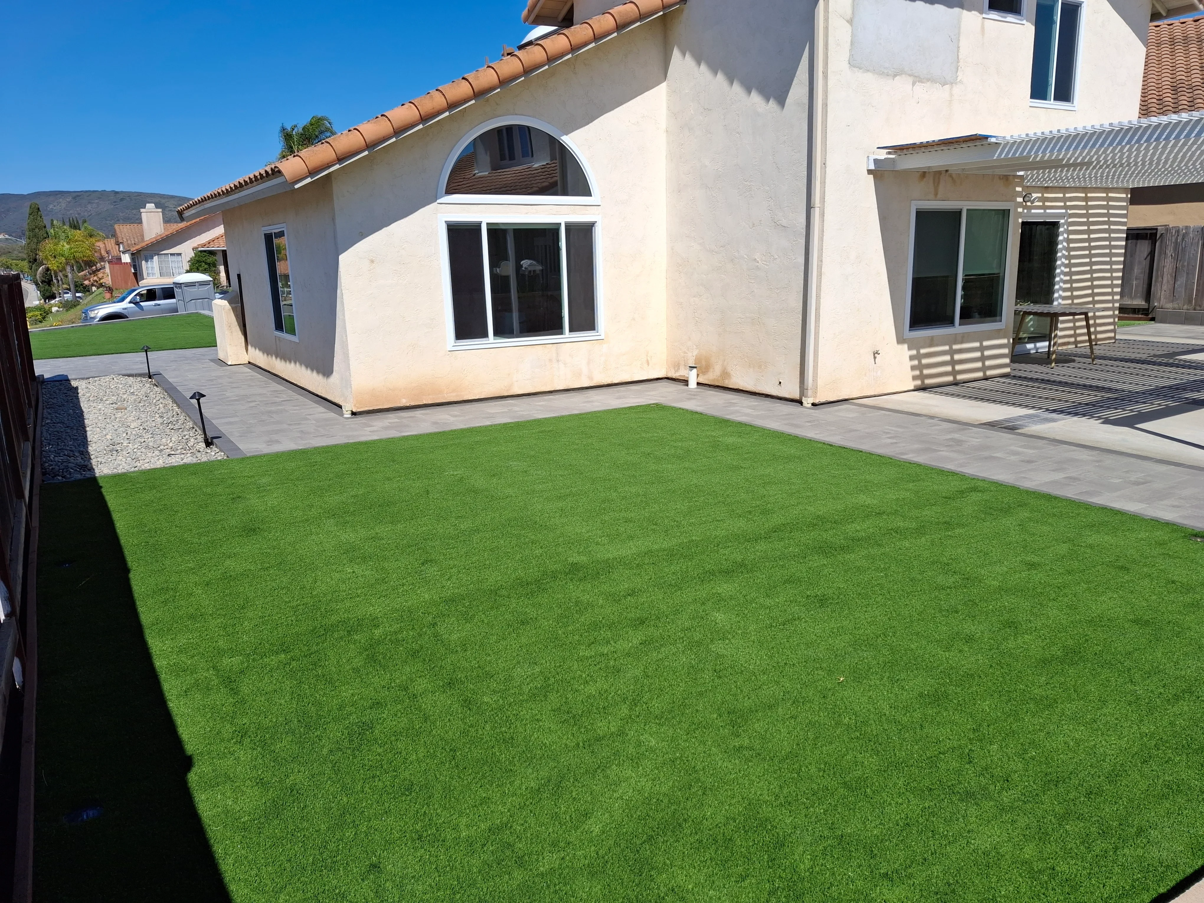 Synthetic turf lawn with gray paver patio and metal landscape edging