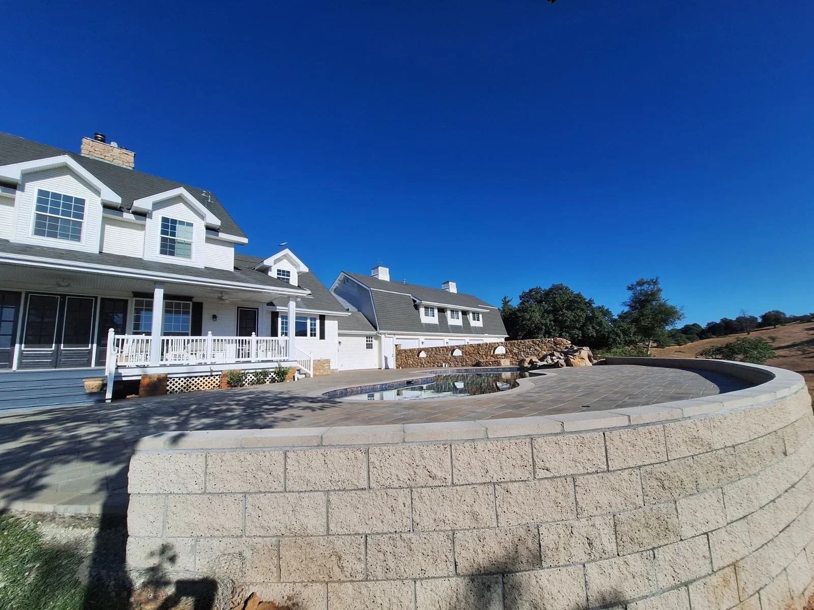Curved pool deck with composite pavers and segmental retaining wall system