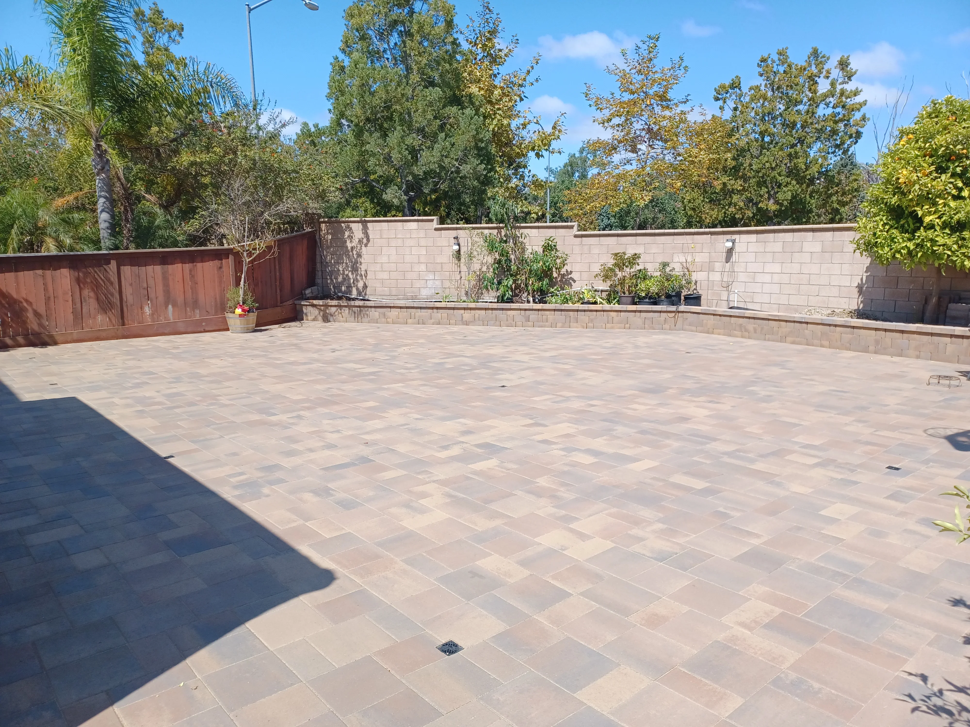 Permeable concrete paver patio with running bond pattern, concrete retaining walls, and wooden fence