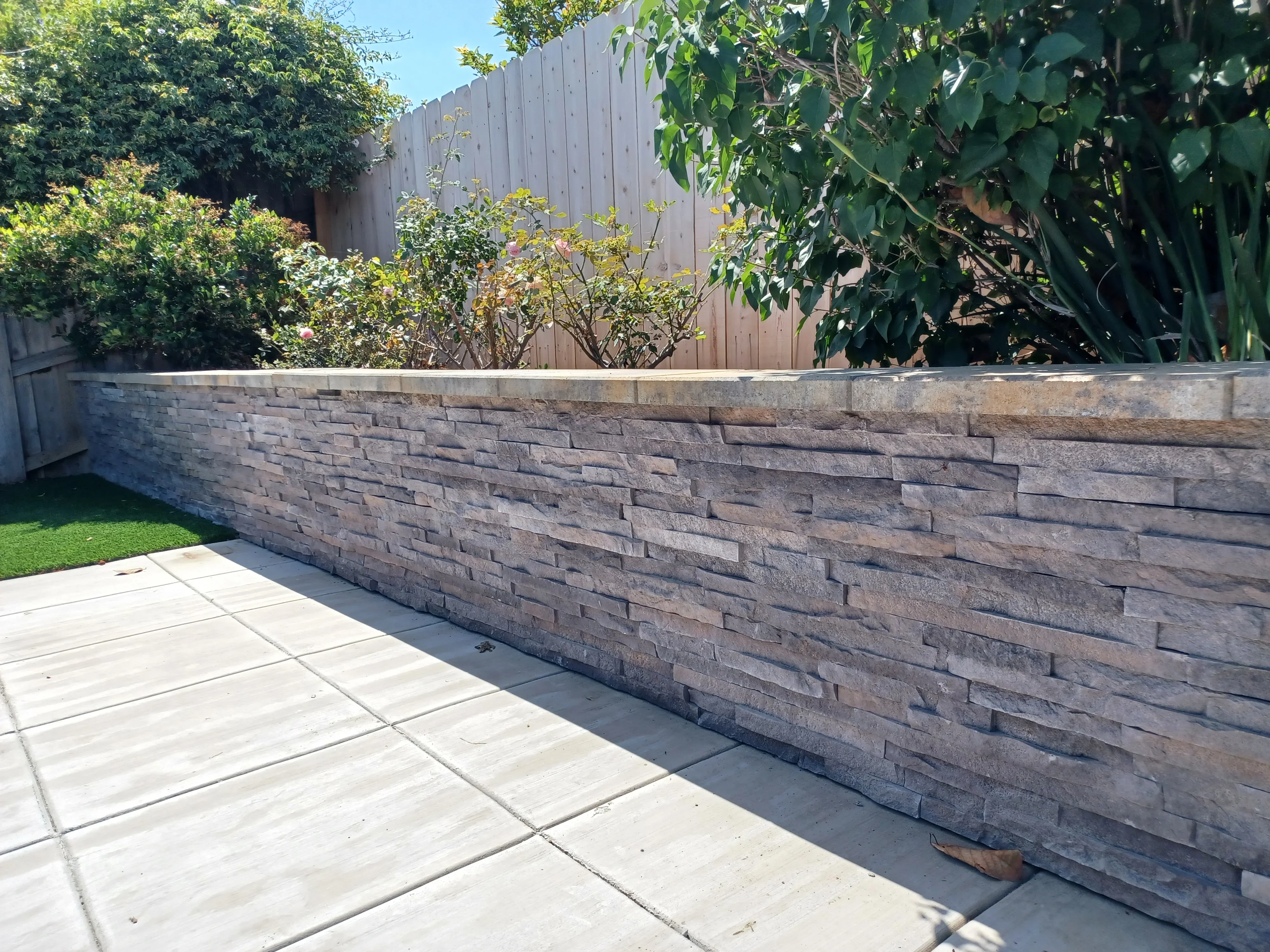 Stacked stone retaining wall with split-face blocks and concrete patio
