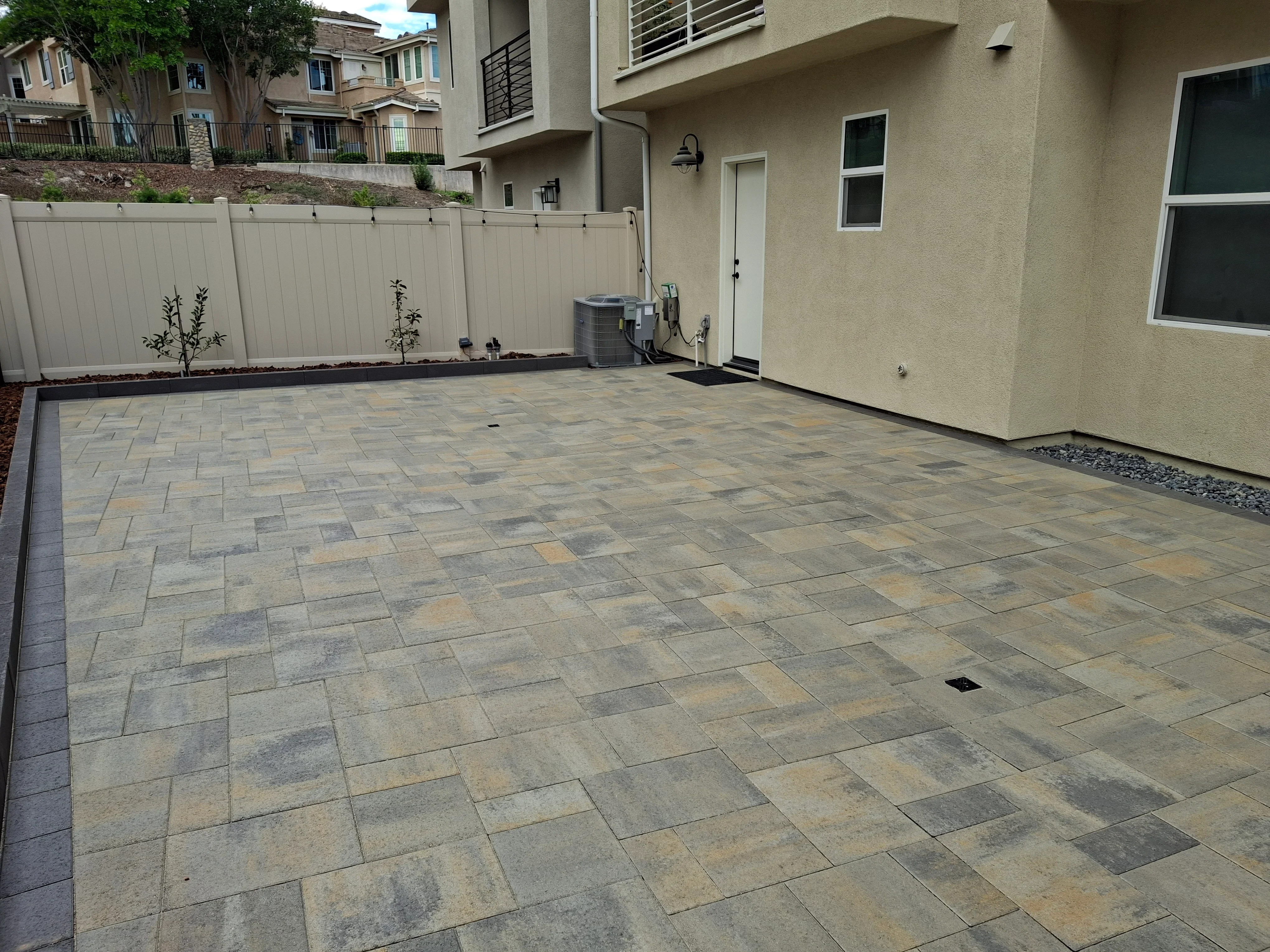 Large permeable paver patio with mixed earth tones in running bond pattern and dark border edge